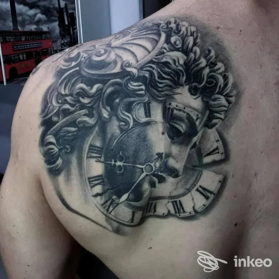 Tatuaggio black&grey su spalla e parte alta della schiena con volto classico e quadrante d'orologio, Camdentown Tattoo Studio, Tivoli.