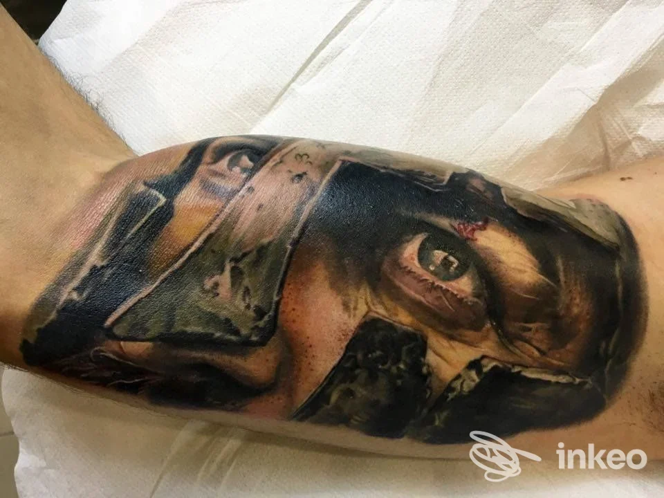 Tattoo realistico di un volto con elmo sul braccio interno, eseguito da Elegant Goat Gallery a Pomezia.