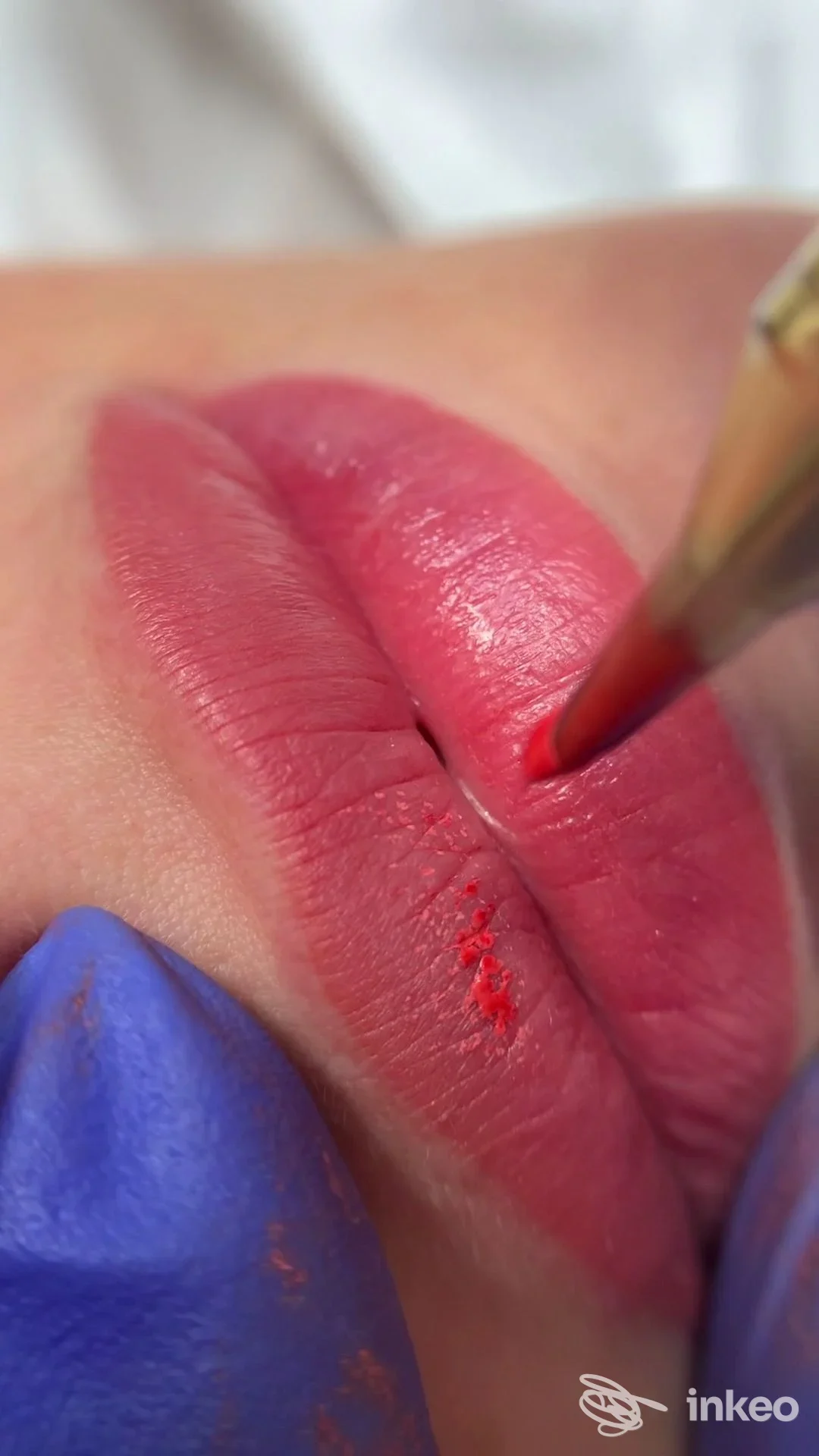 Primo piano di dermopigmentazione labbra eseguita da Face Harmony Studio, Roma; operatore con guanto blu e strumento mentre deposita pigmento.
