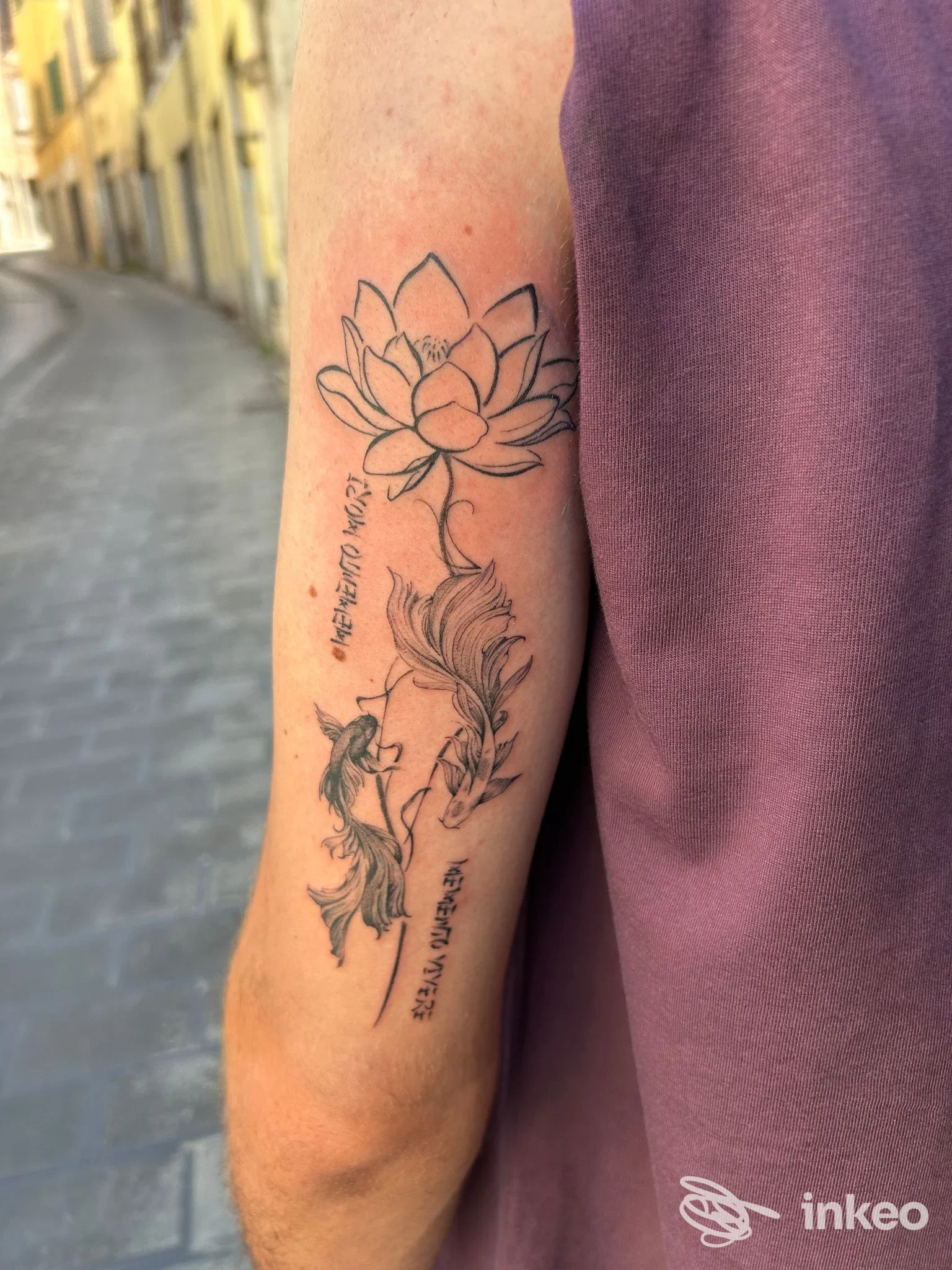 Tatuaggio a inchiostro nero con loto e pesci sull'avambraccio, scatto fornito da Industrial ink, Frosinone.