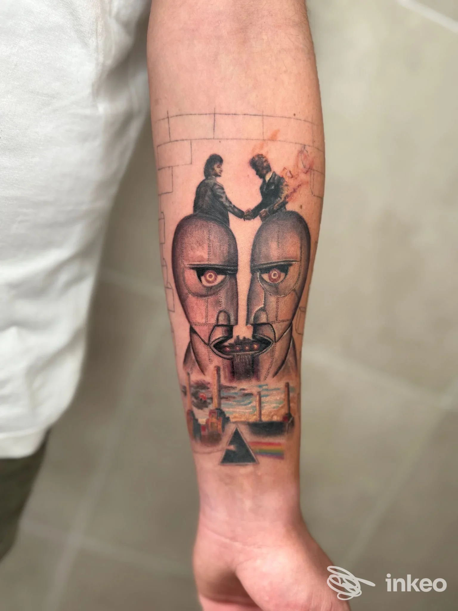 Tatuaggio su avambraccio con volti stilizzati e prisma colorato, foto di Guna Tattoo Lab a Santi Cosma e Damiano.