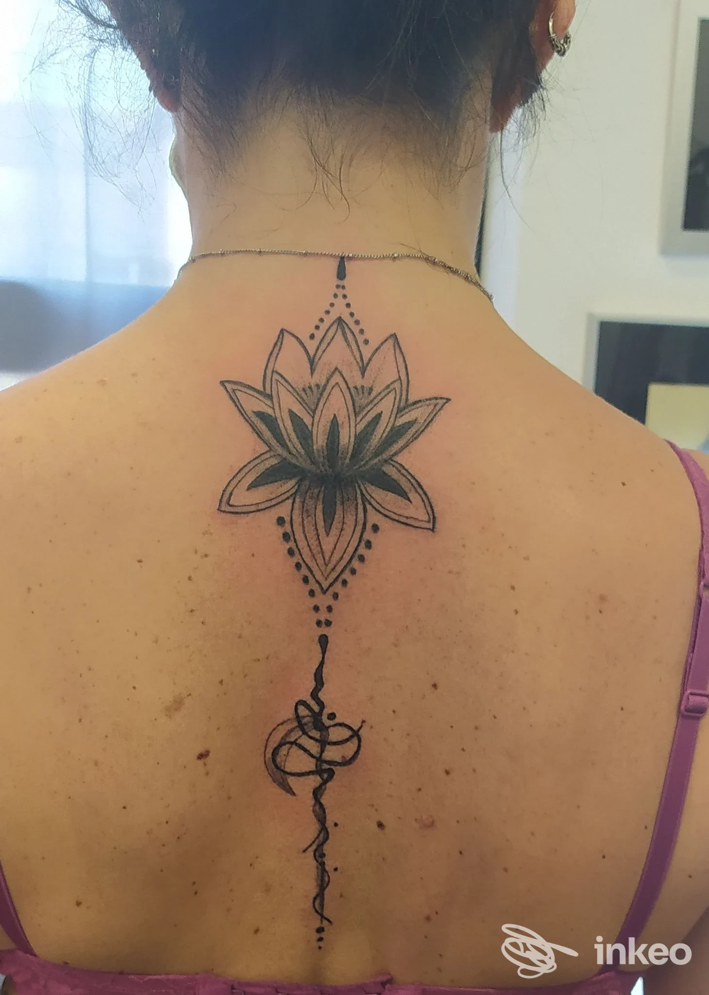 Grande tatuaggio floreale stilizzato lungo la colonna cervicale su schiena di donna, realizzato da Nina Tattoo a Roma.