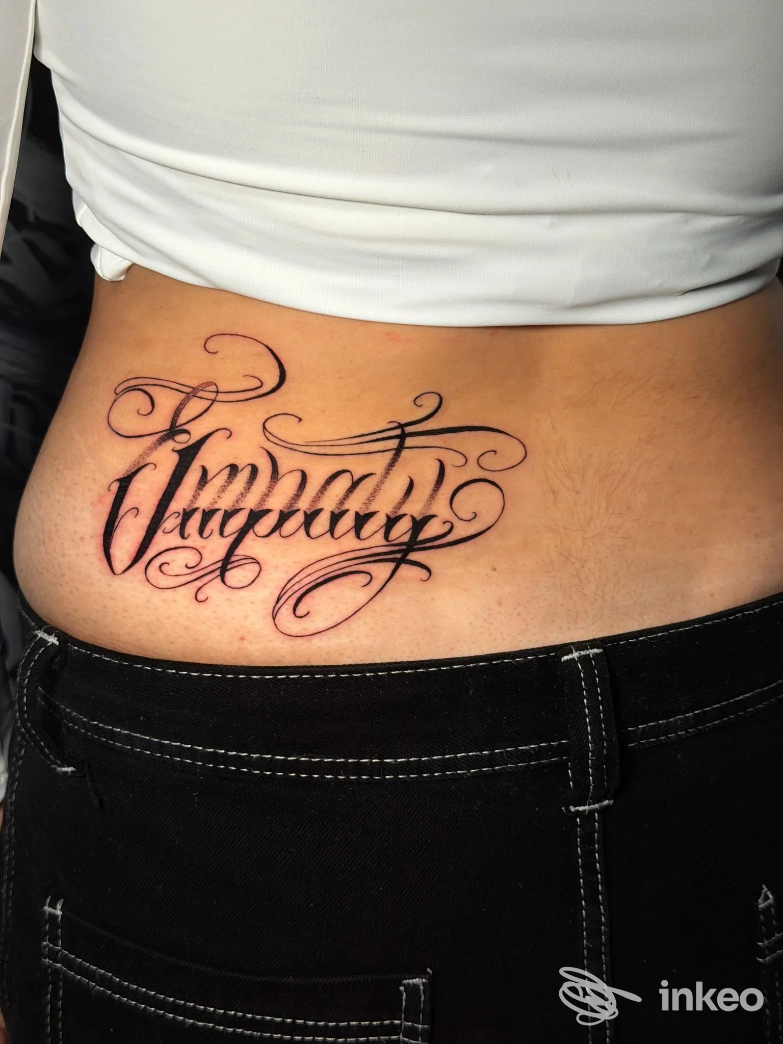 Tatuaggio calligrafico sul fianco/lombare realizzato da Square Mentality Marconi a Roma.