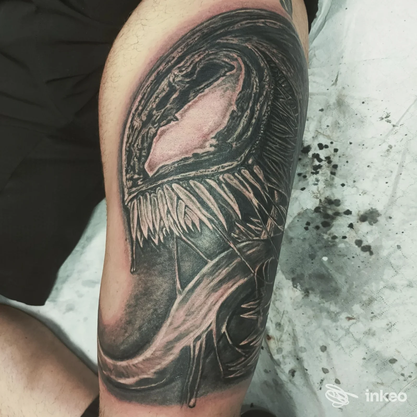 Tatuaggio realistico in bianco e nero su avambraccio raffigurante una testa mostruosa con denti e lingua. Studio inkanto beauty e tattoo, Roma.