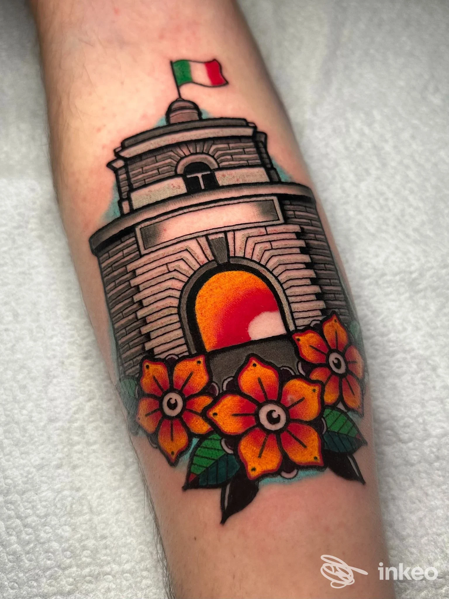 Tatuaggio a colori su avambraccio con monumento, tramonto e fiori, realizzato da TrameNoireInk, Roma.