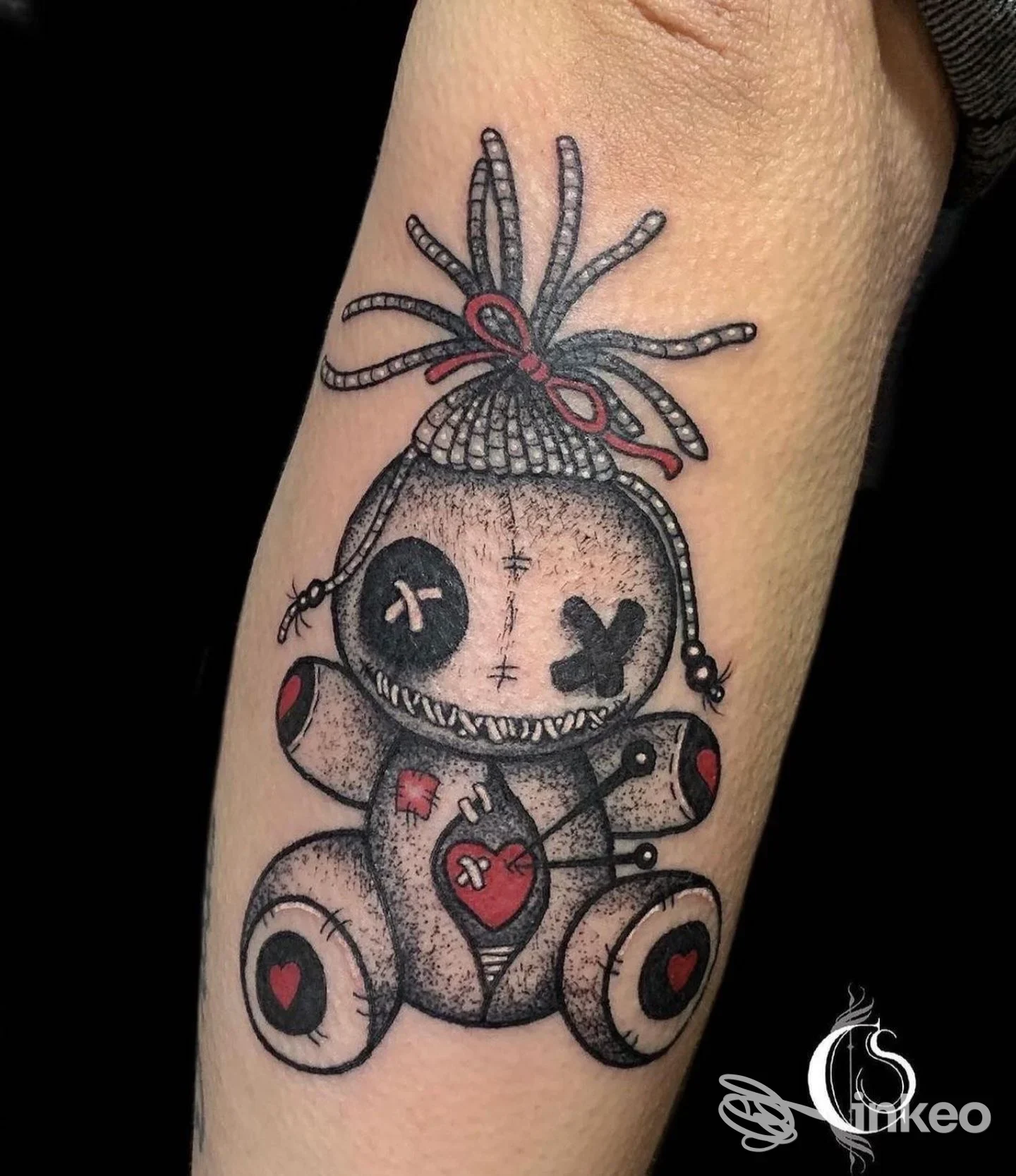 Tatuaggio su avambraccio raffigurante una bambola voodoo stilizzata con dettagli neri e rossi, Vecchie Maniere Tattoo e Piercing, Roma