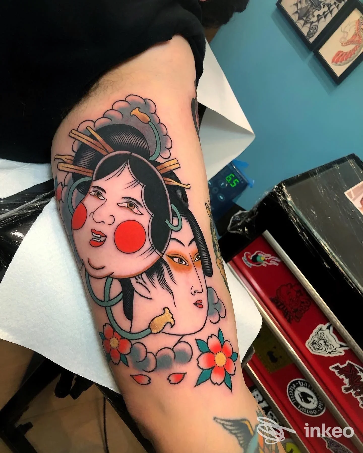 Tatuaggio a colori su braccio superiore con volti stilizzati e fiori, scatto in studio Well Done Tattoo Shop, Roma.