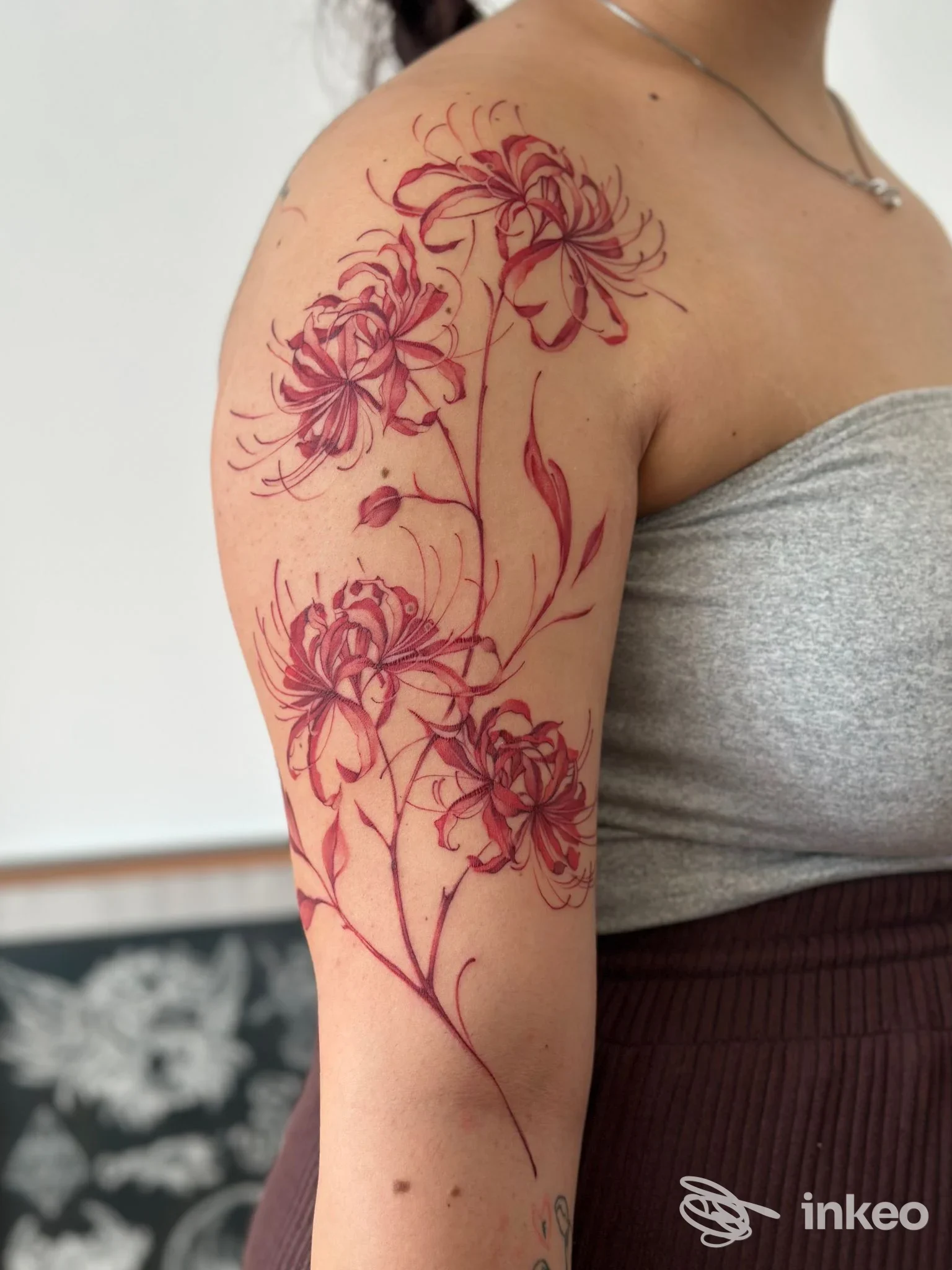 Ampio tatuaggio floreale rosso sul braccio superiore e spalla, foto inviata da 741 Tattoo Parlour Vallecrosia a Vallecrosia al Mare.
