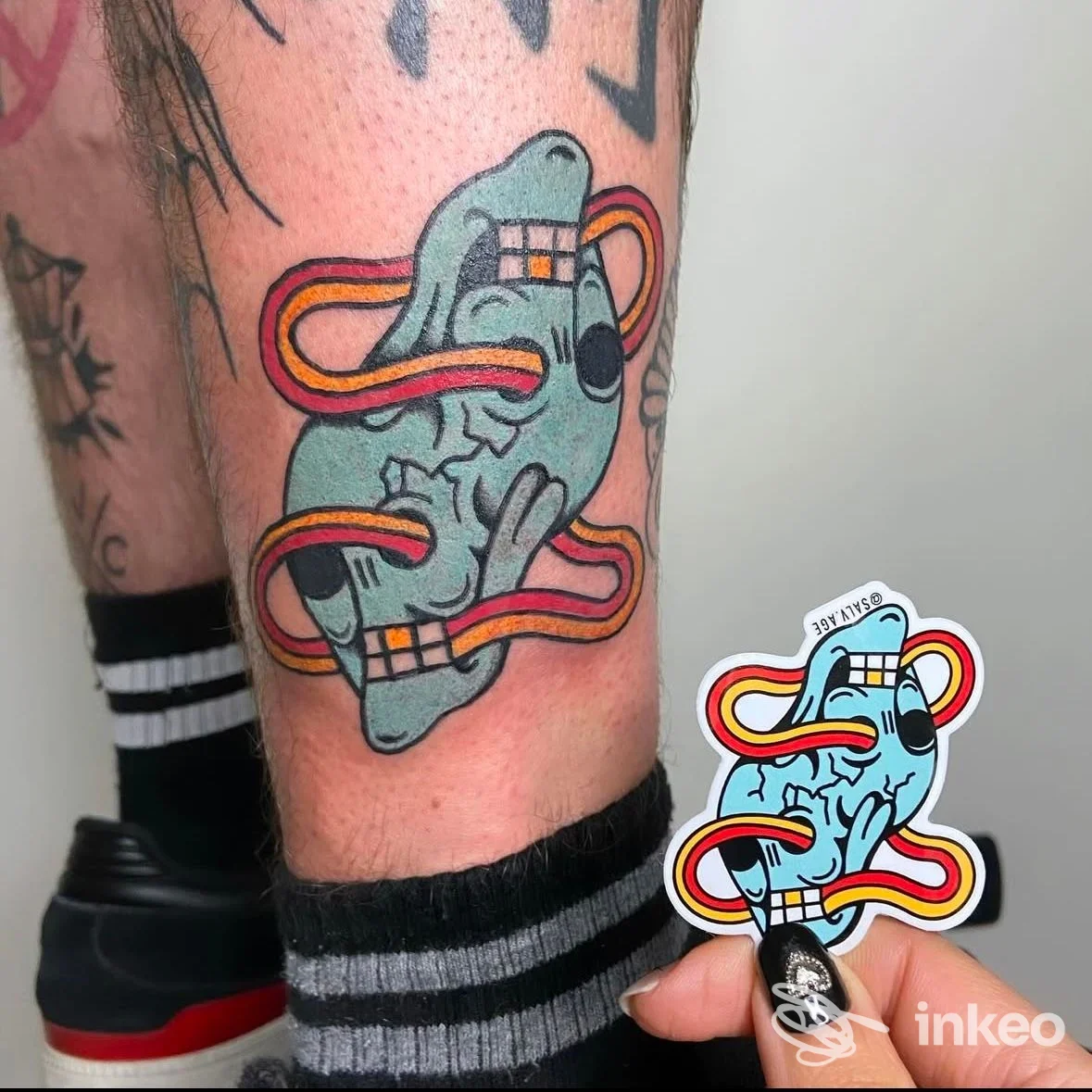 Tatuaggio colorato su gamba con design a nastro, 741 Tattoo Parlour Vallecrosia al Mare.