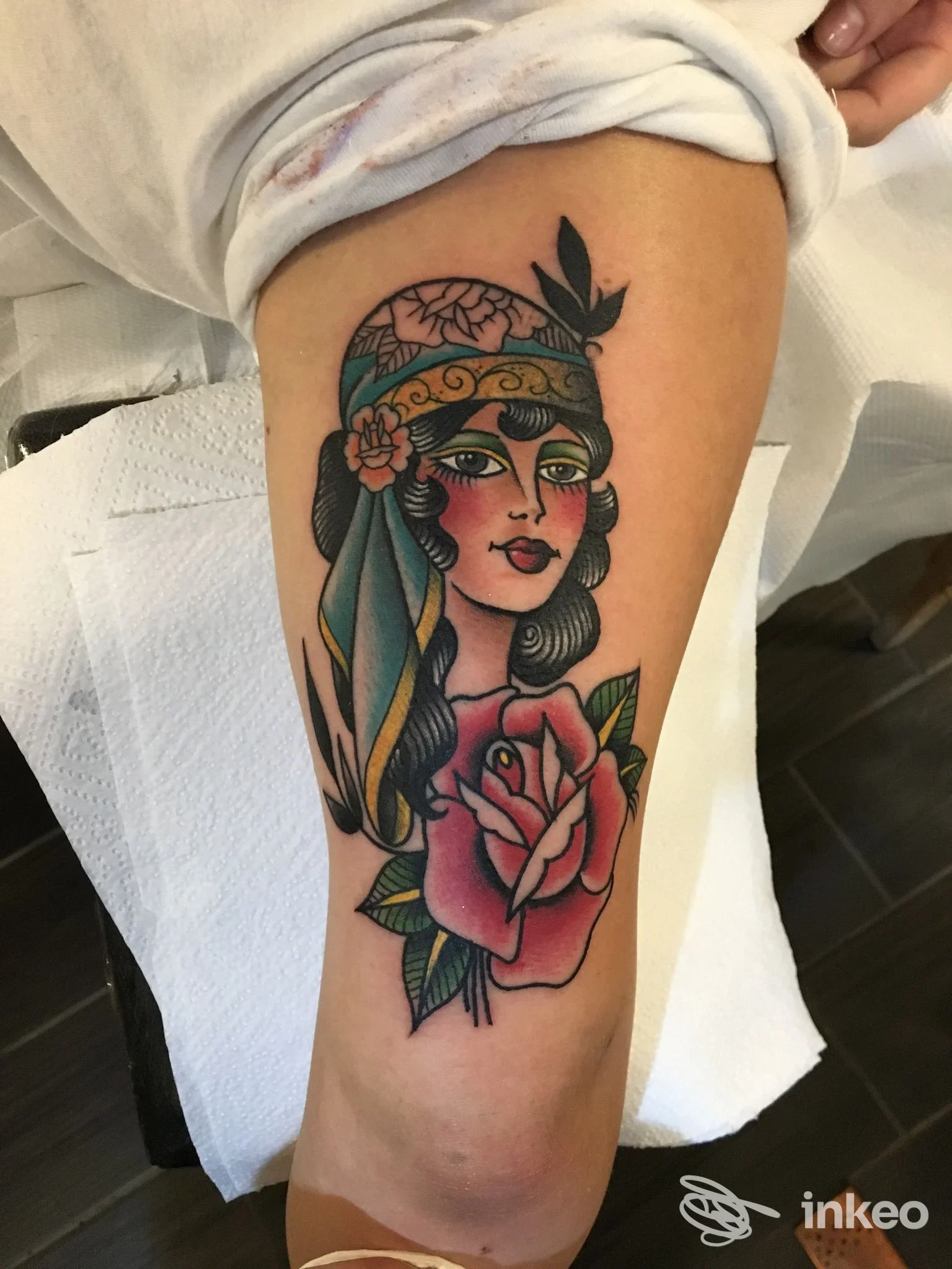 Tatuaggio tradizionale di volto femminile con rosa sulla parte superiore della gamba; foto fornita dallo studio AME Tattoo, Genova.