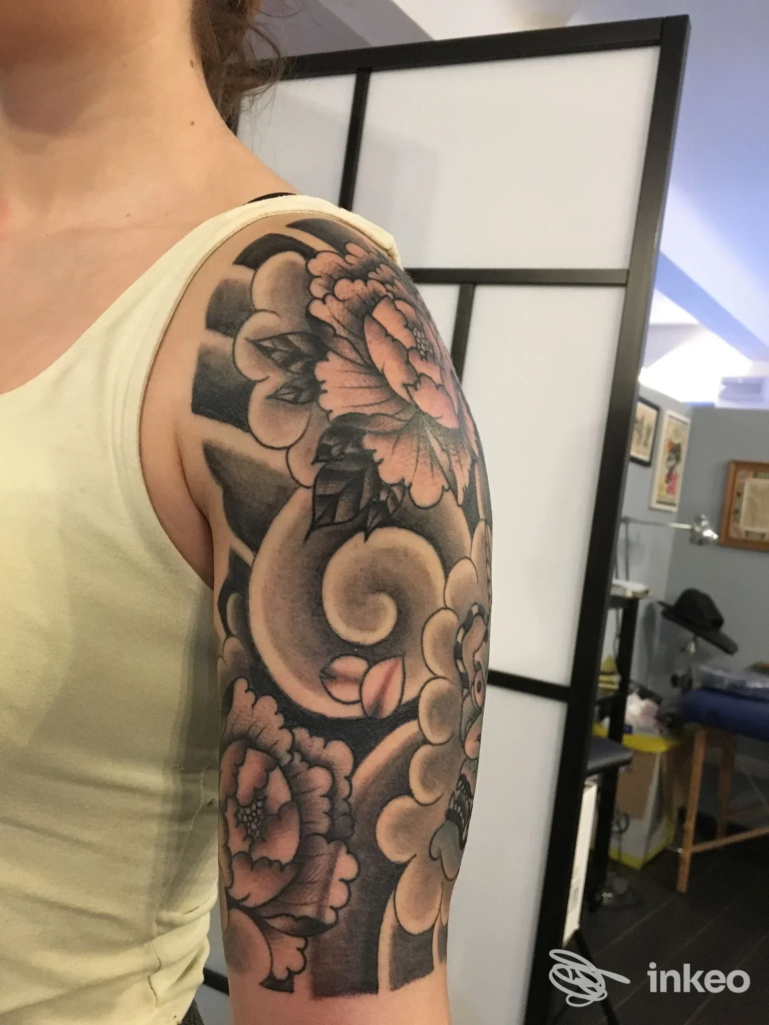 Tatuaggio floreale in nero e sfumature sulla spalla e parte alta del braccio, foto fornita da AME Tattoo, Genova.
