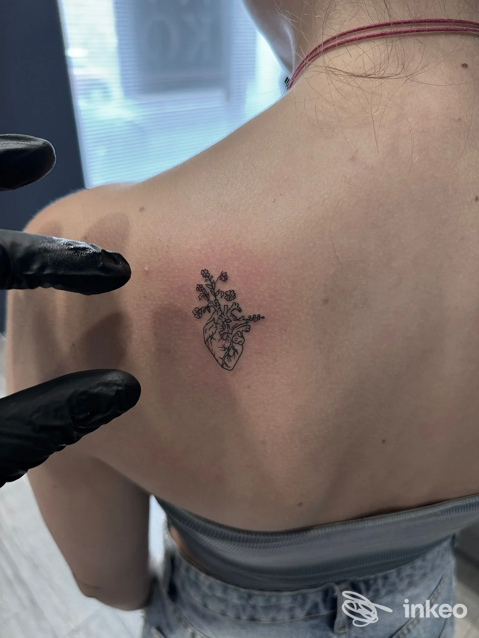 Piccolo tatuaggio botanico a forma di cuore anatomico sulla parte superiore della schiena, eseguito da Niko Tattoo Studio a Ventimiglia.