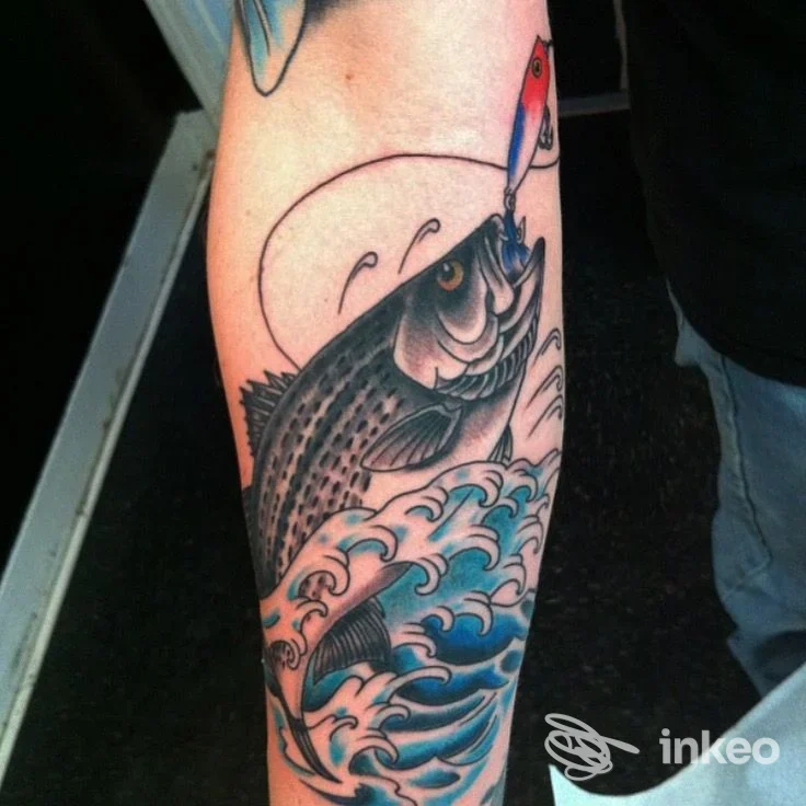 Tatuaggio tradizionale di un pesce che salta tra onde blu sull'avambraccio, fotografato presso American Grace Tattoo Studio a Sestri Levante.