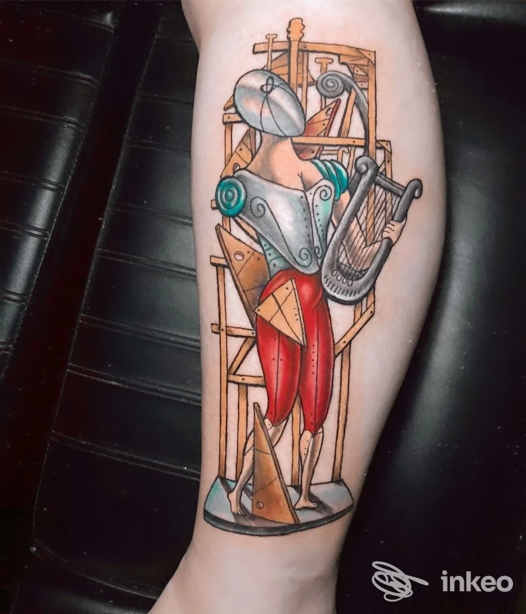 Tatuaggio figurativo e geometrico sul polpaccio, realizzato da Atelier Tattoo di Rocco Inserra a Recco, con colori rossi e toni turchesi.