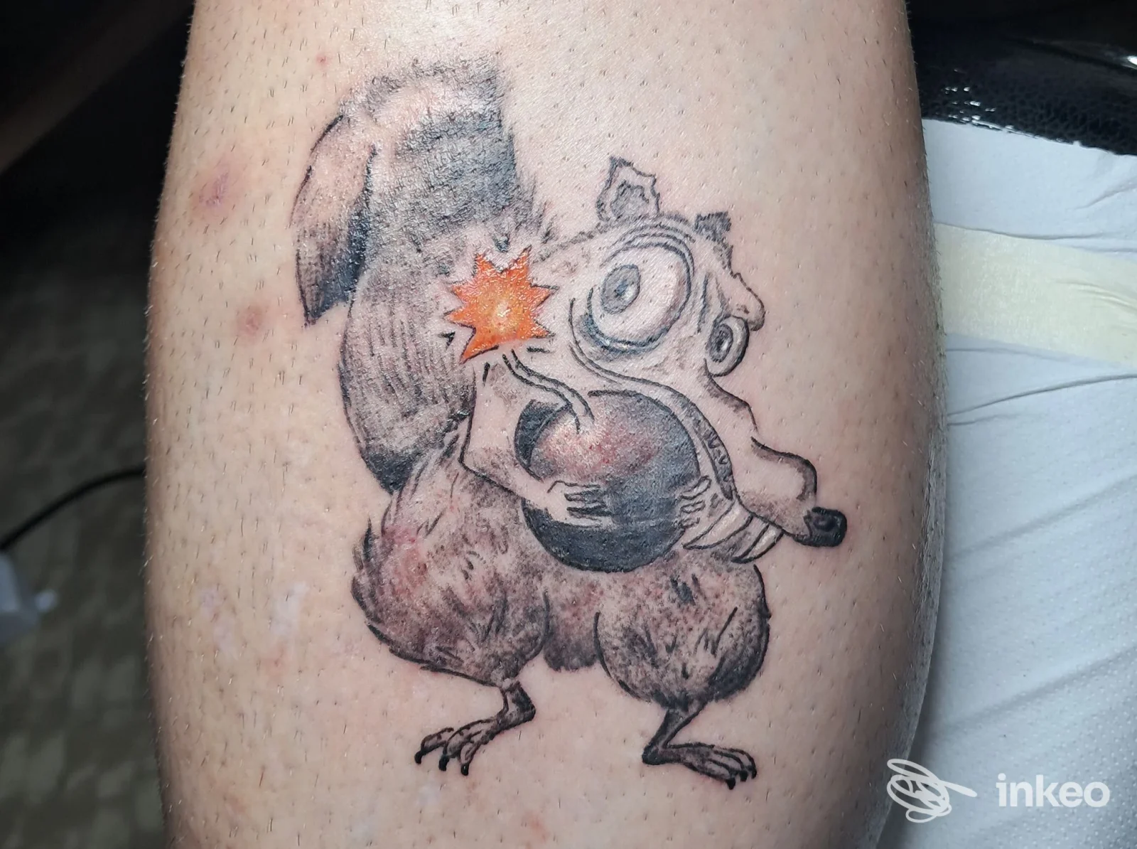 Tatuaggio cartoon su polpaccio realizzato da Be happink tattoo, Cairo Montenotte: creature che tiene una palla con esplosione arancione.