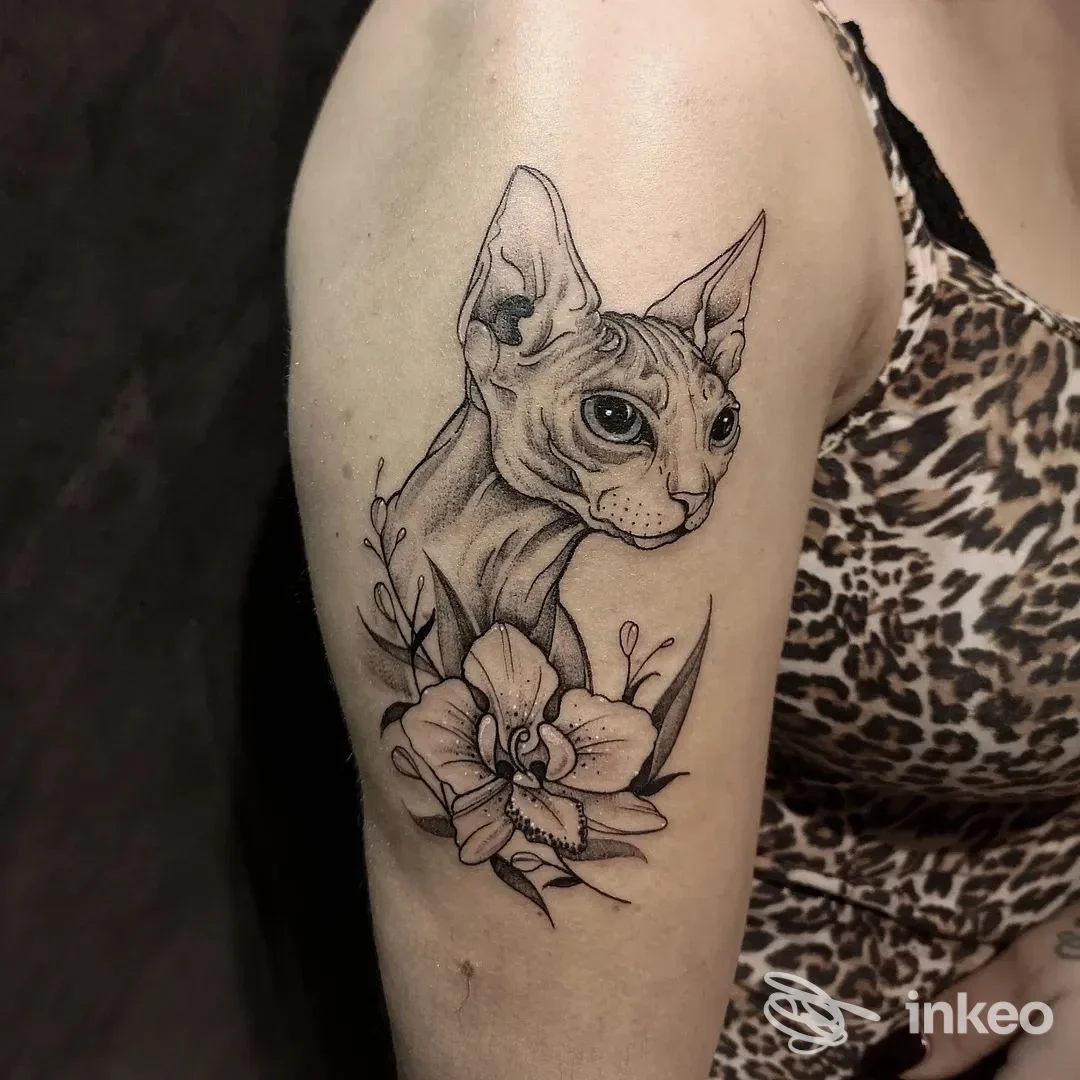 Tatuaggio sul braccio con ritratto di gatto Sphynx e fiori, foto fornita da Black Nun Tattoo a Diano Marina.