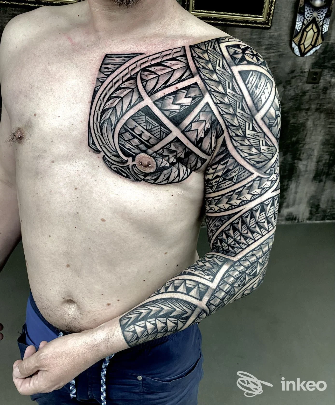 Tattoo geometrico in bianco e nero su braccio e torace di una persona senza camicia, eseguito su pelle reale, stile geometrico, Street Art Tattoo.