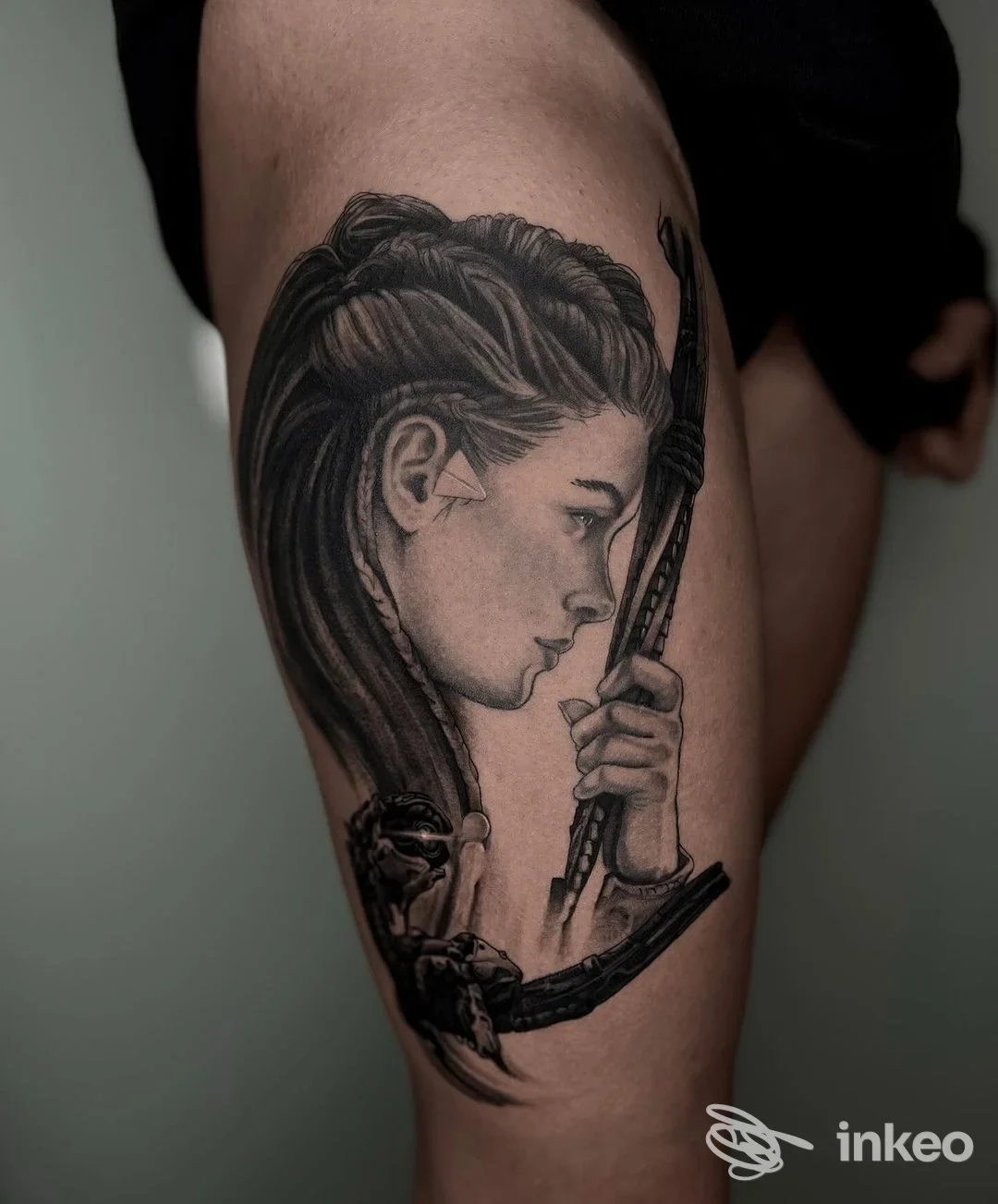 Tatuaggio realistico in bianco e nero su coscia raffigurante profilo femminile con arco, foto da Belink La Tatueria a Bussana, Sanremo.