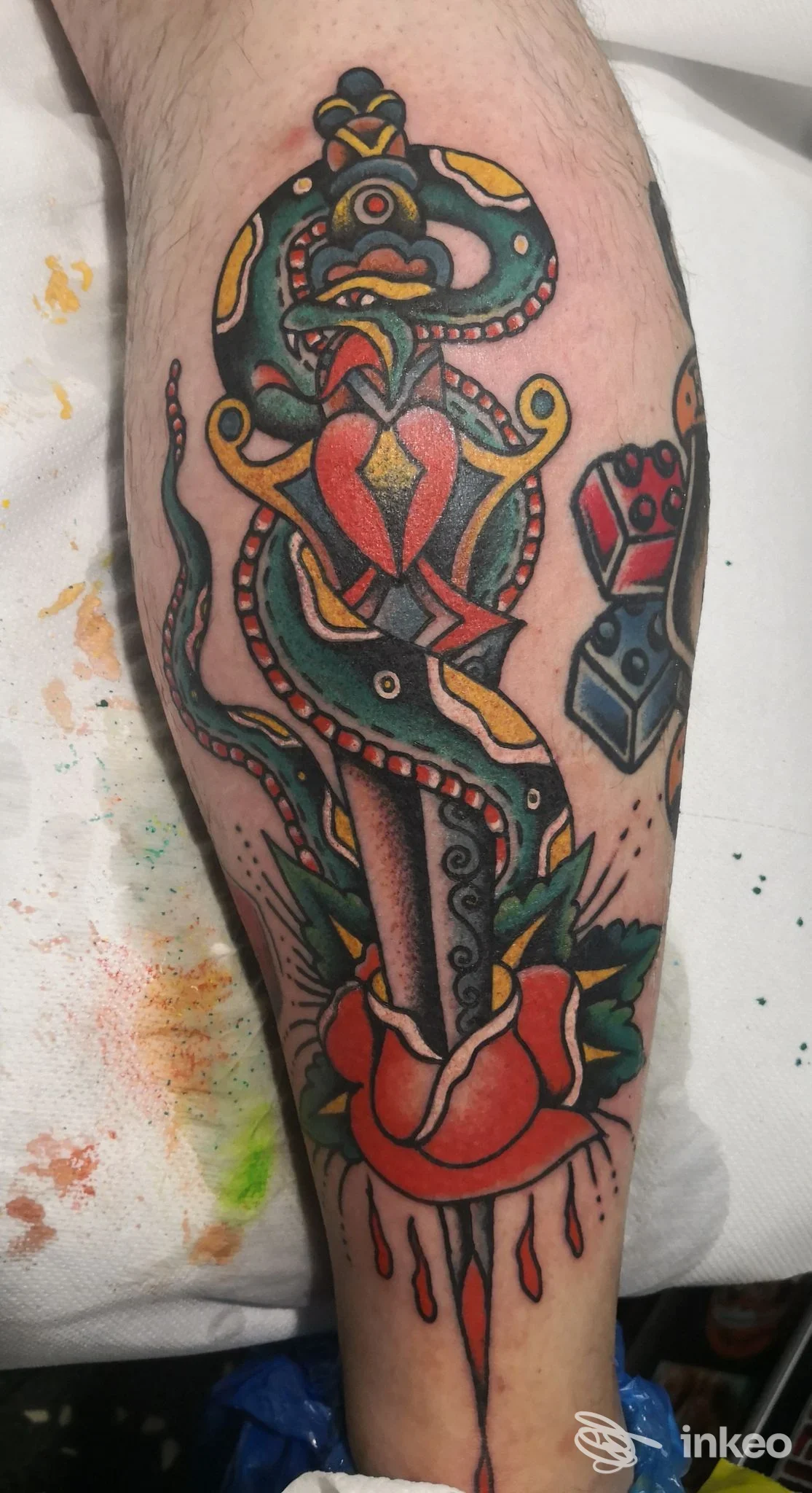 Tatuaggio tradizionale su polpaccio: pugnale avvolto da serpente e rosa, colori pieni e linee nette. Eseguito da Blue Port Tattoo, Genova.