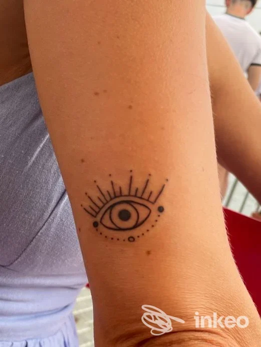 Tatuaggio nero stilizzato a forma di occhio sull'avambraccio, Blue Port Tattoo, Genova.