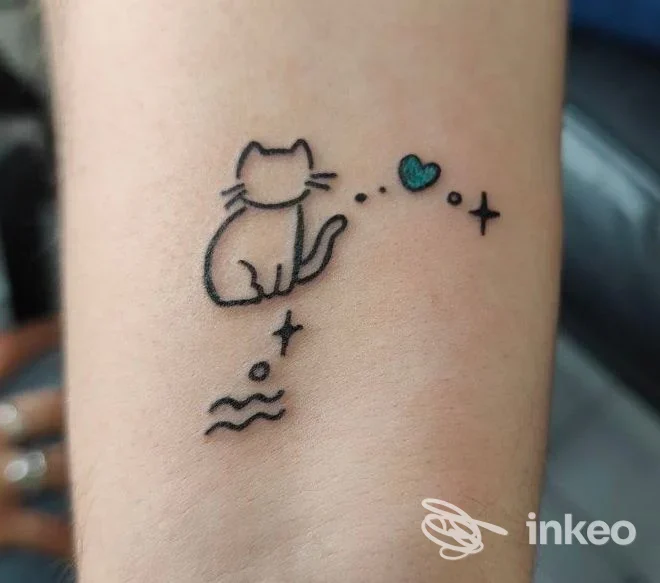 Piccolo tatuaggio lineare di un gatto con cuore colorato sull'avambraccio. Immagine fornita da BonnyTattoo studio, Genova.