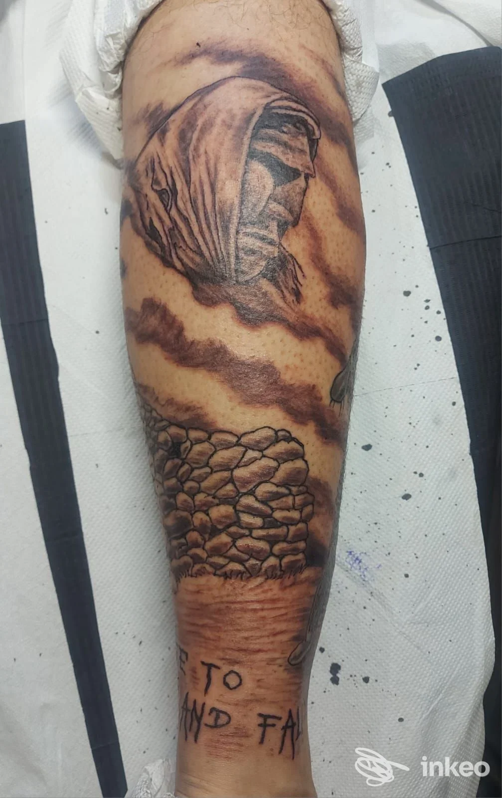 Tatuaggio su avambraccio con figura incappucciata e muro di pietra, foto dallo studio Dreams Maker Tattoo & Piercing a Genova.