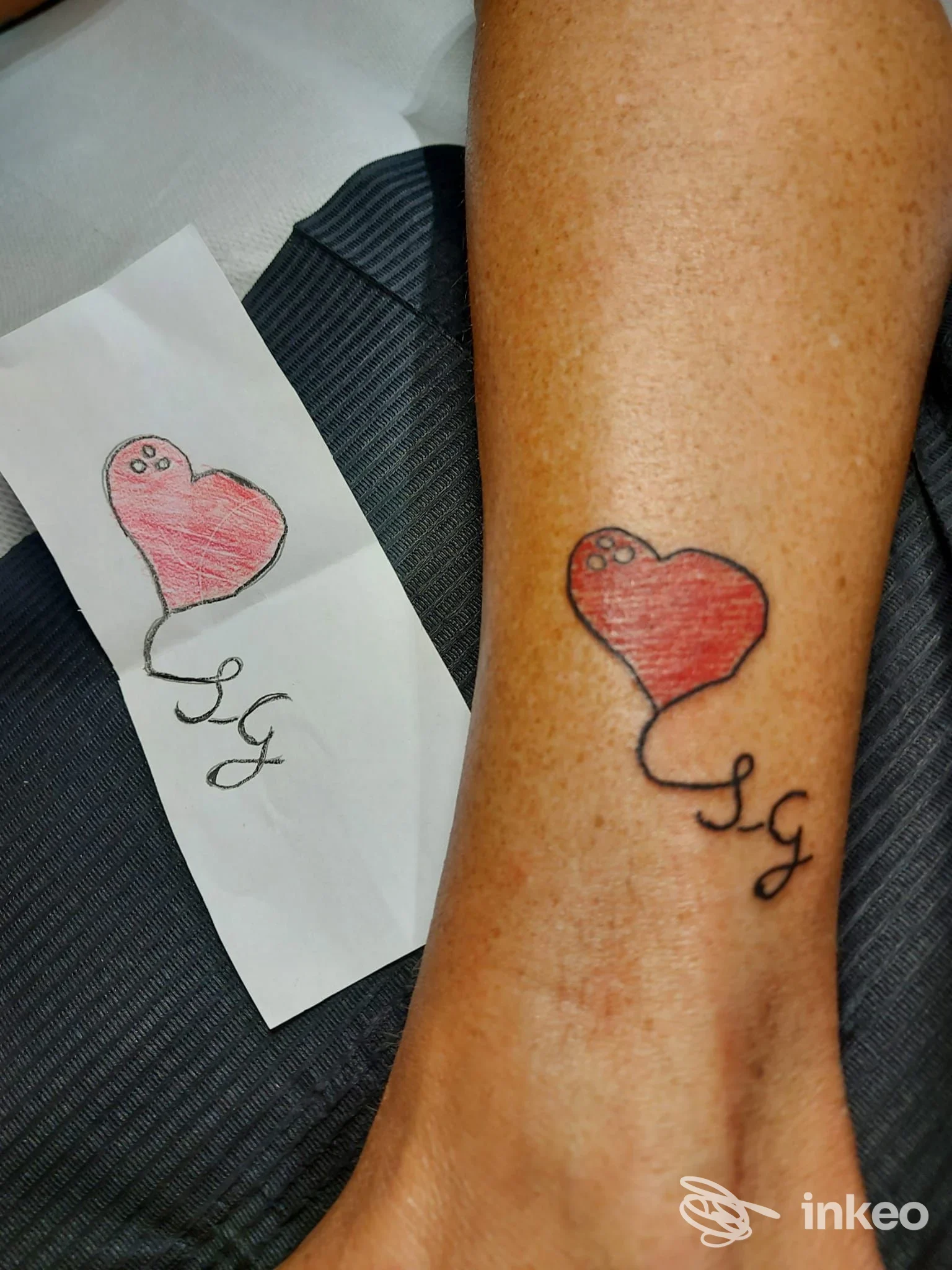 Tatuaggio a forma di cuore rosso con iniziali sulla caviglia, fotografia fornita da Dreams Maker Tattoo & Piercing, Genova.