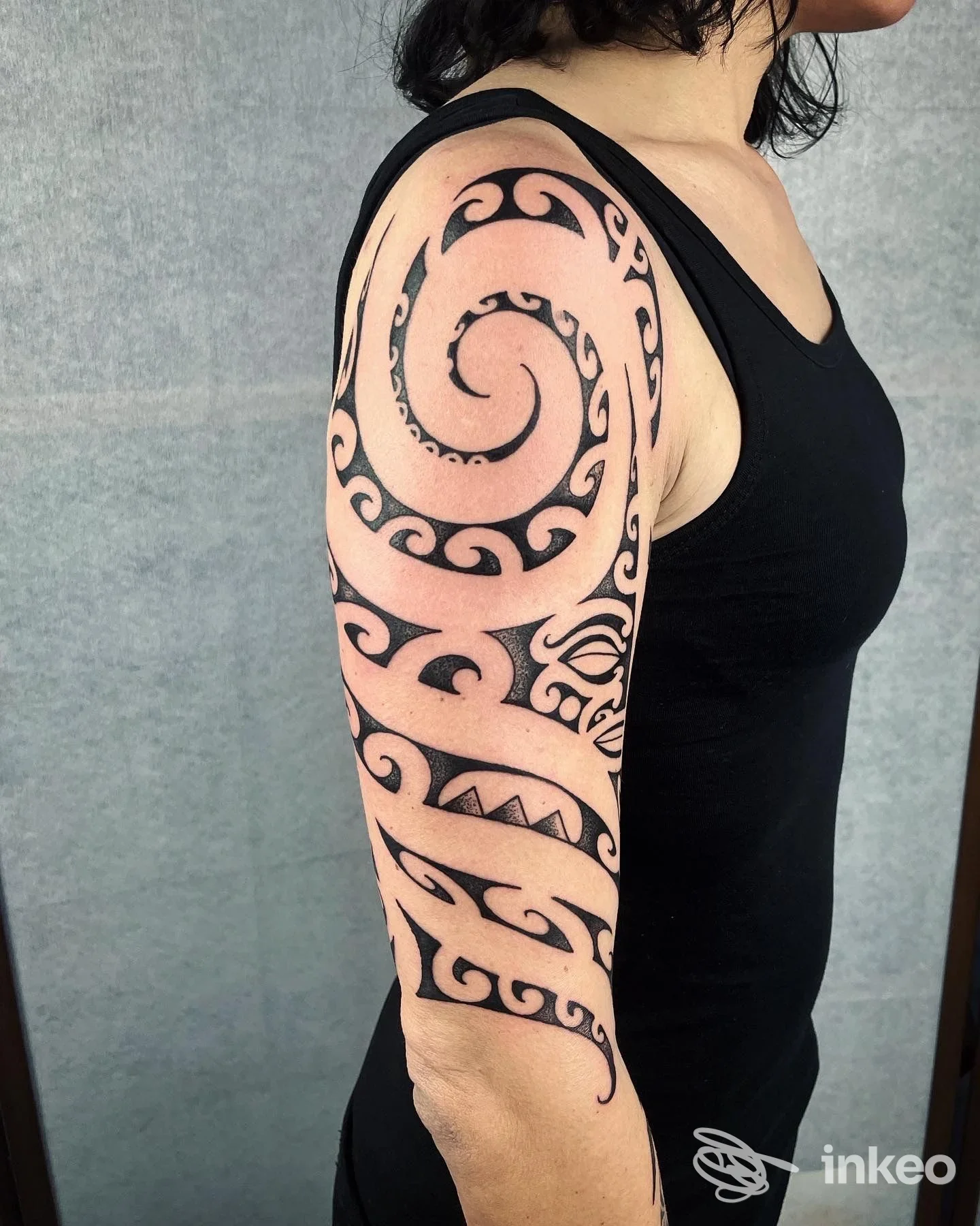 Ampio tatuaggio tribale nero su spalla e braccio superiore, fotografato su una persona; lavoro di Ettore Groccia Tattoo a Genova.