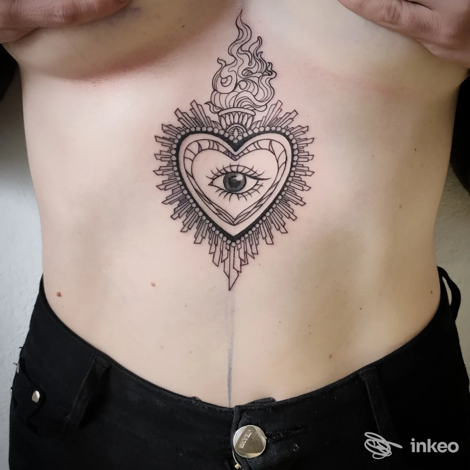 Tatuaggio a linee nere a cuore con occhio centrale sullo sterno, Dreams Tattoo Studio, Marina di Andora.