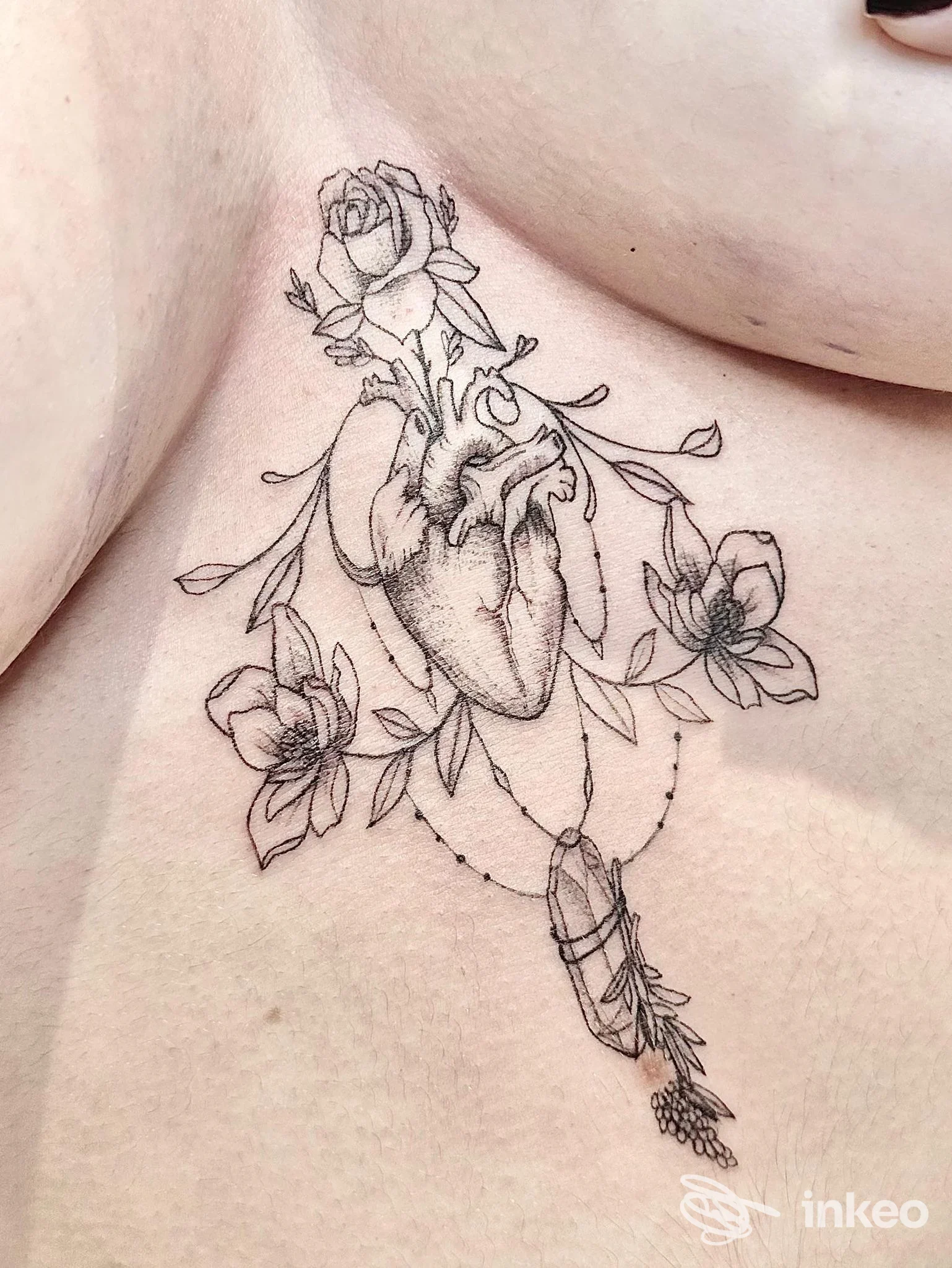Tatuaggio a linework sul torace: cuore anatomico con fiori e pendente. Francesca Accardo Tattoo Artist, Romito Magra.