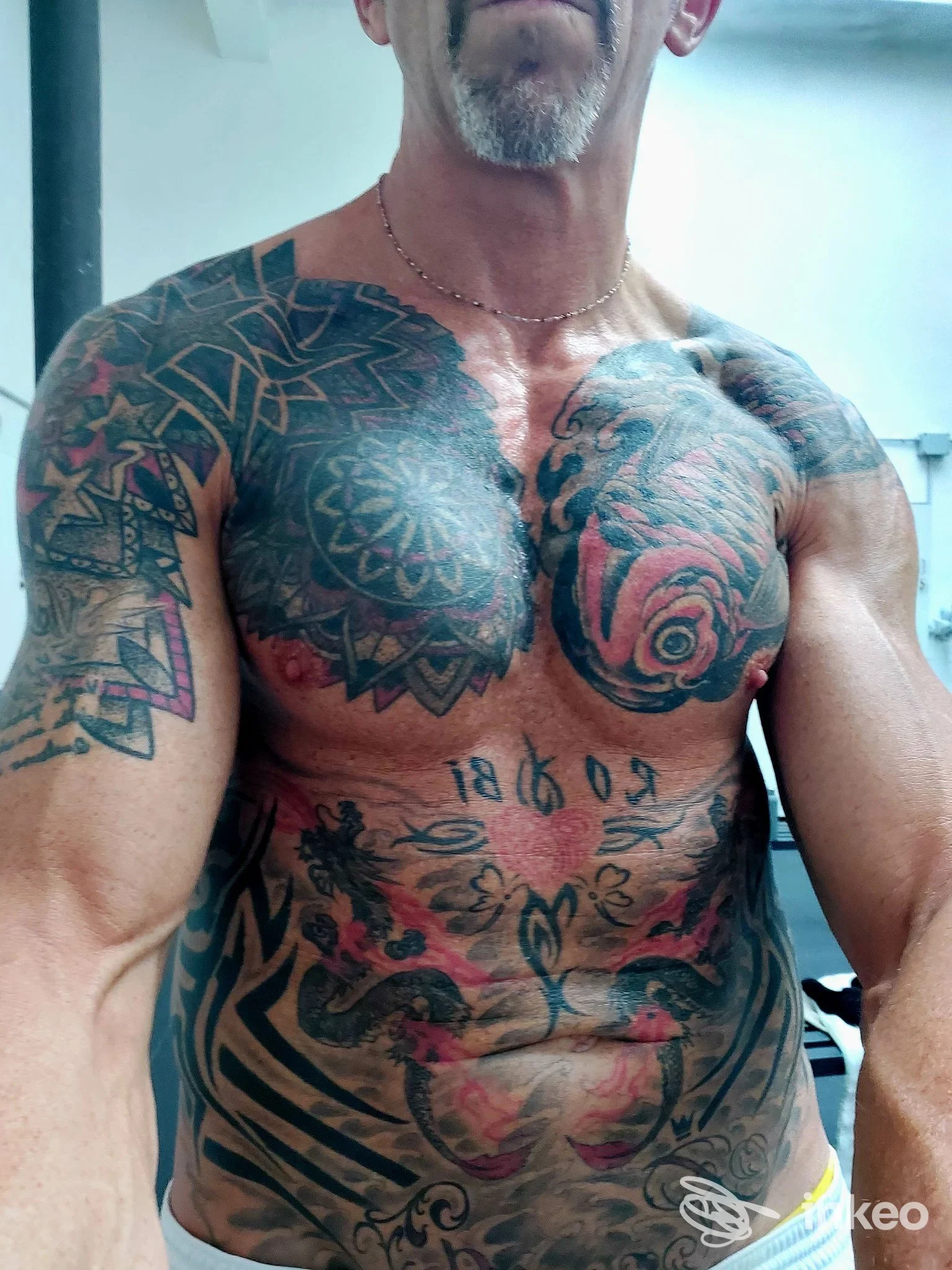 Uomo con ampi tatuaggi ornamentali su torace, addome e braccia, foto per Franzo Tattoo Family a Rapallo.