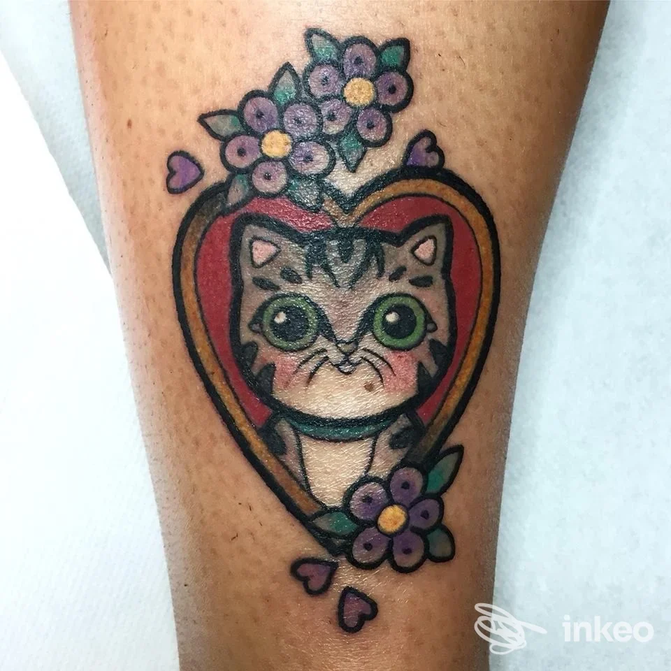 Tatuaggio a colori di un gattino in un cuore con fiori, eseguito da Hari Onago Tattoo Studio a La Spezia, su polpaccio.