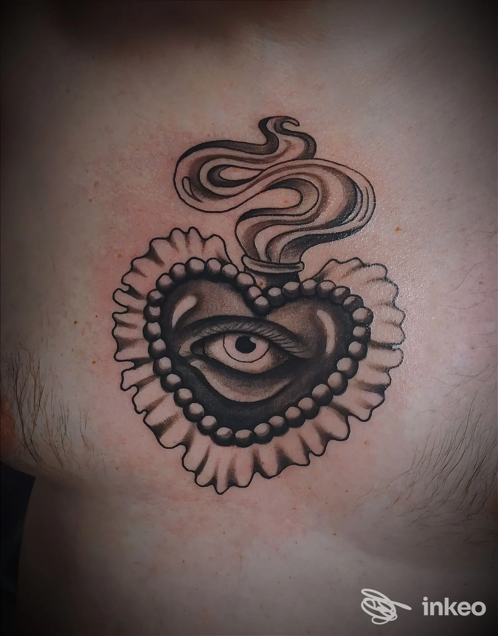 Tatuaggio a cuore con occhio stilizzato sul petto, eseguito da Gocce Proibite Tattoo Studio a Finale Ligure.