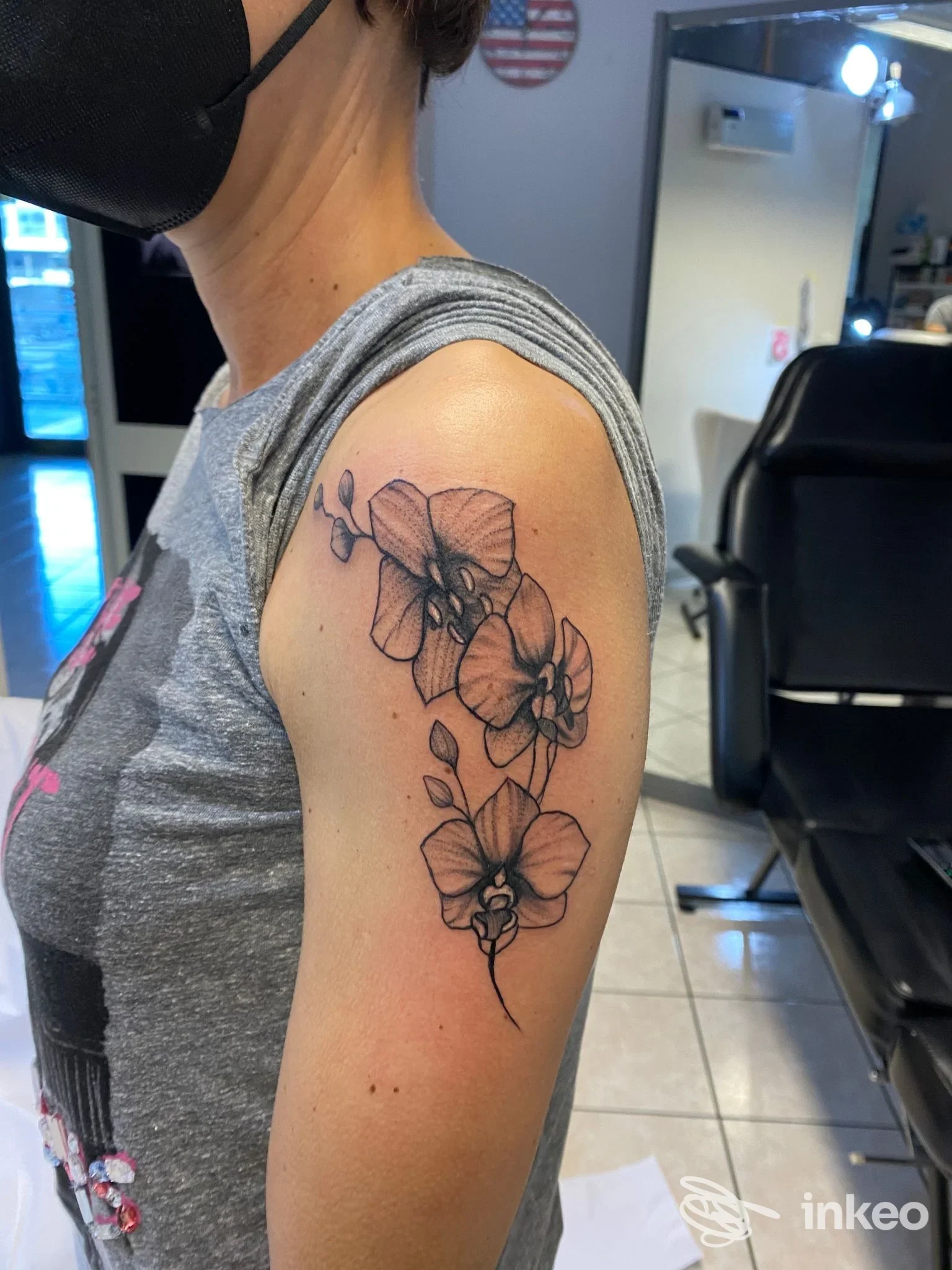 Foto del tatuaggio floreale sull'omero effettuato da J Tattoo La Spezia, La Spezia: tre orchidee in nero e grigio disposte verticalmente.