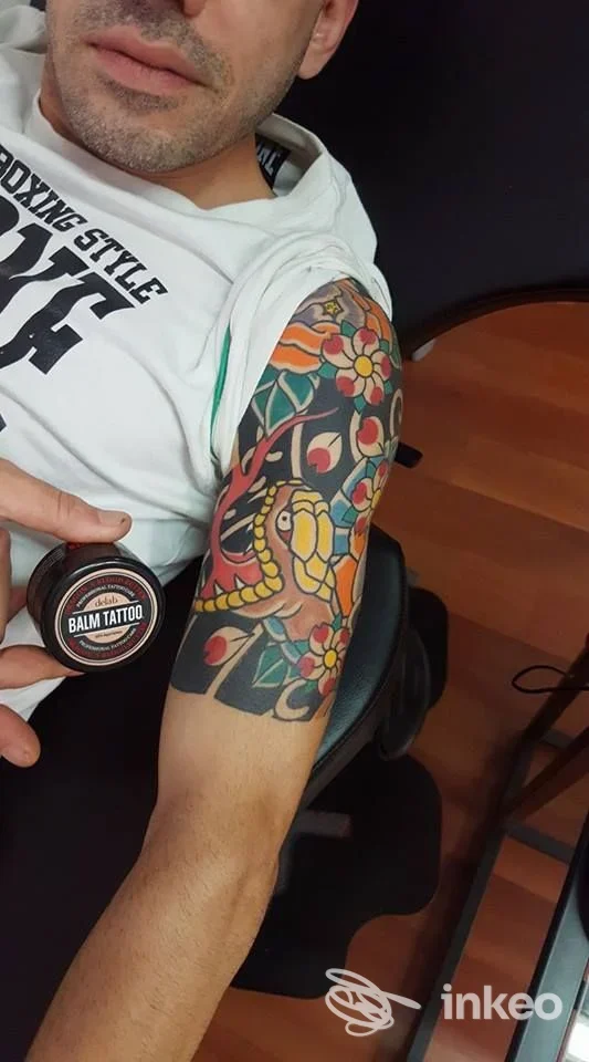 Dettaglio tatuaggio colorato sul braccio superiore, foto dello studio Juri Tattooing Genova a Genova; volto dell'uomo visibile in parte.