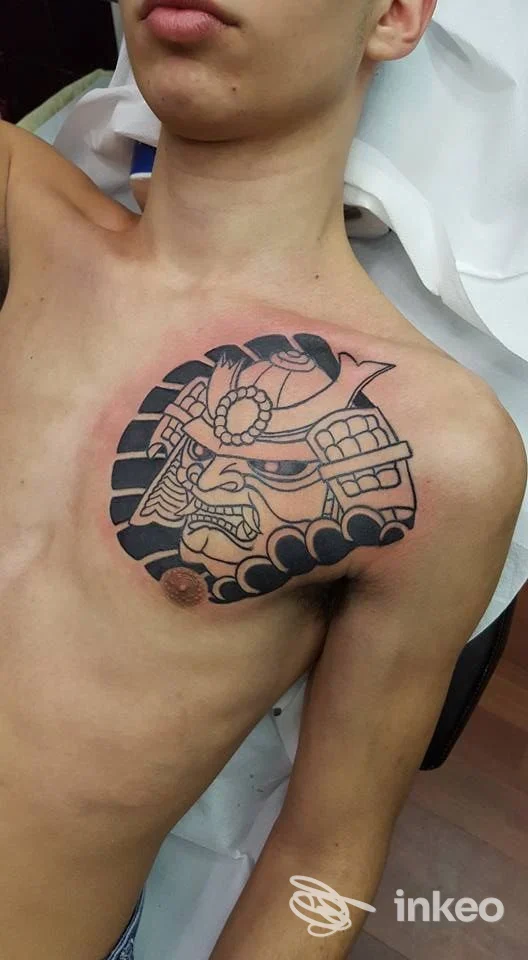 Tatuaggio su petto sinistro raffigurante una maschera stilizzata, foto fornita da Juri Tattooing Genova, Genova.