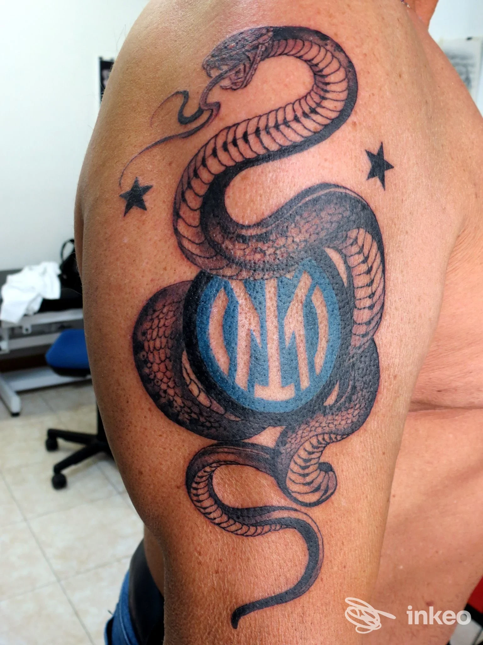 Tatuaggio a serpente nero con motivo circolare blu sul braccio, foto fornita da Igor Tattoo, Sanremo.