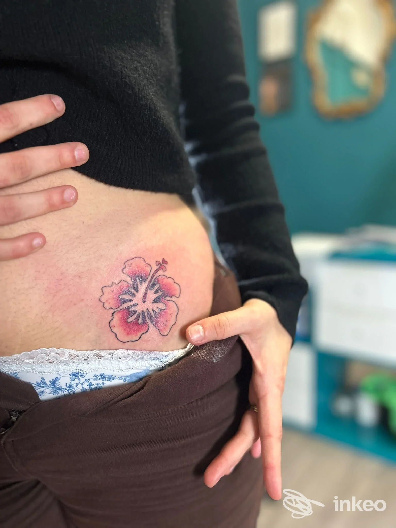 Primo piano di un tatuaggio floreale rosa sul basso addome, foto fornita da La Dolce Vita Tattoo Studio, Genova.