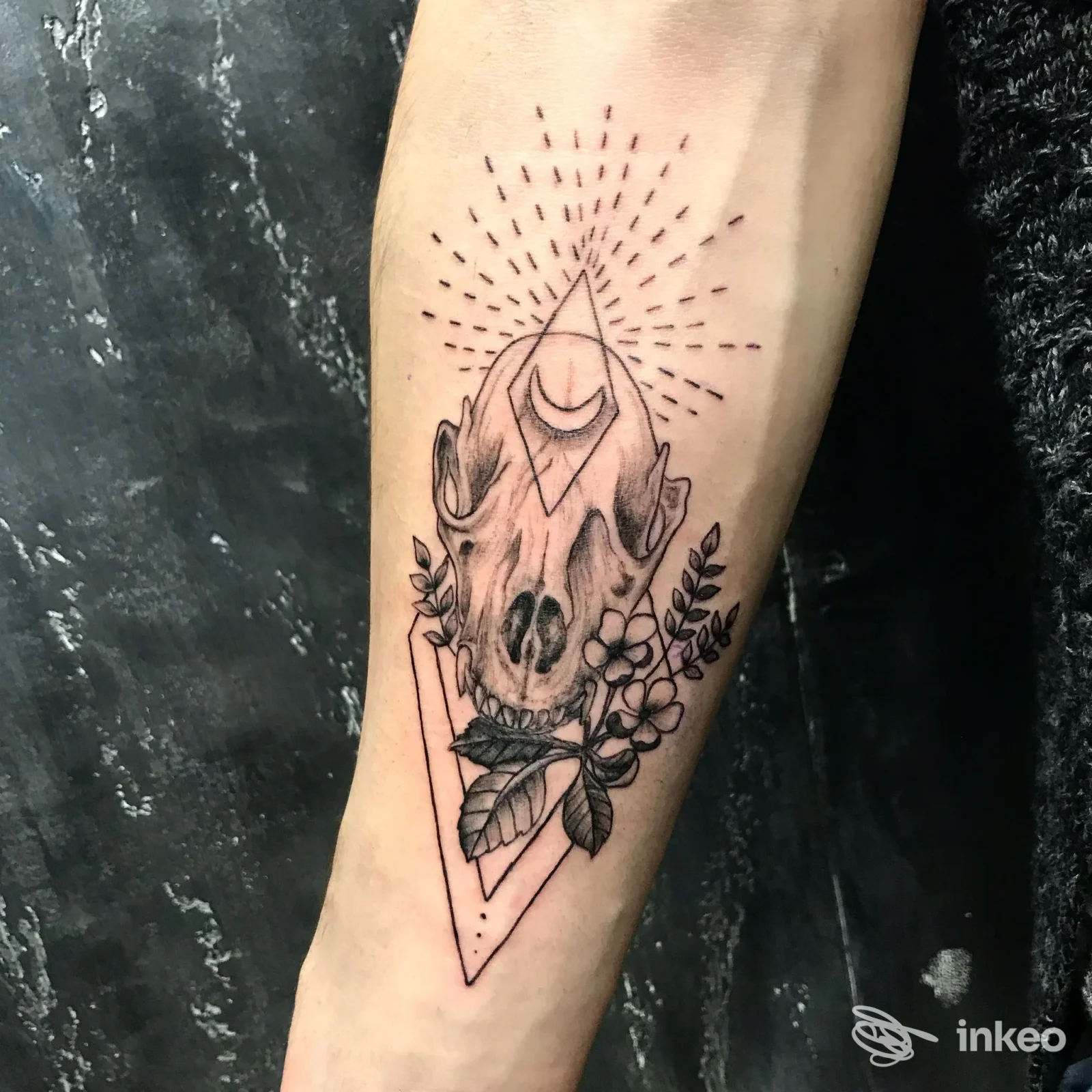 Tatuaggio in bianco e nero su avambraccio con teschio animale, forme geometriche e fiori, foto fornita da La Perla Nera Tattoo Studio, Arenzano.