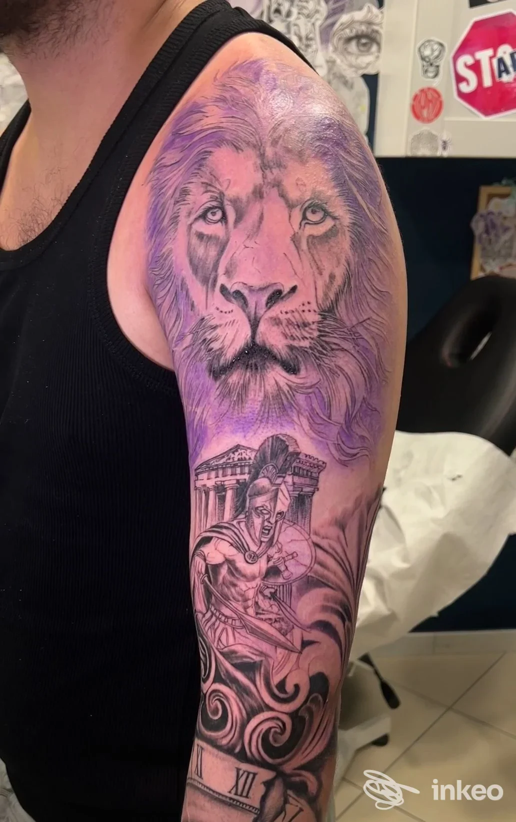 Grande tatuaggio realistico di un leone e una scena con guerriero sulla spalla e braccio superiore, fotografato a La Raza Tattoo Studio a La Spezia.