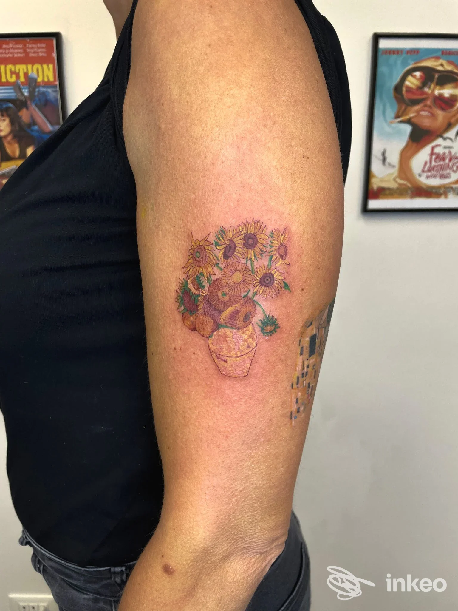 Tatuaggio floreale su braccio superiore esterno realizzato da Maison René Tattoo a La Spezia: vaso con girasoli e fiori colorati.