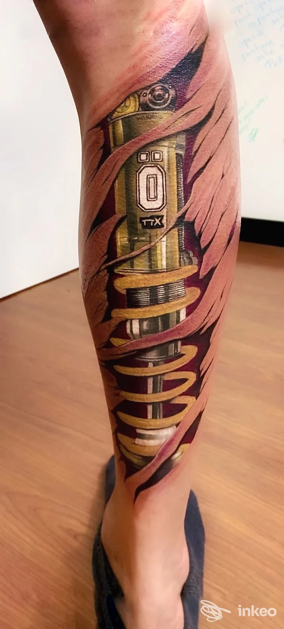 Primo piano di polpaccio con tatuaggio biomeccanico a effetto pelle strappata, MAGMA_TATTOO Lavagna.