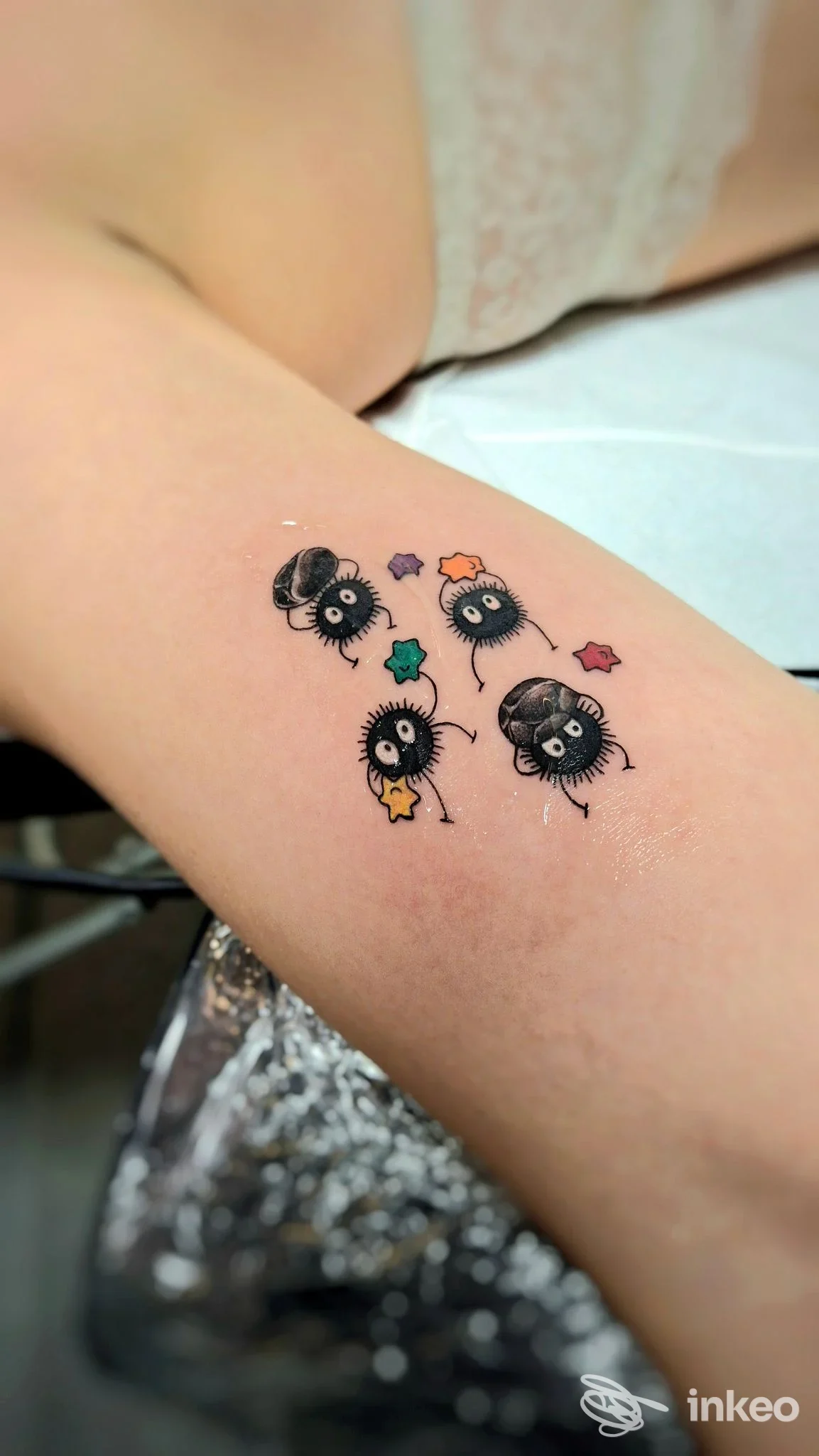 Piccolo tatuaggio a inchiostro nero con personaggi stilizzati e stelline colorate sull'avambraccio, Miriaddormento Tattoo Studio, Chiavari.