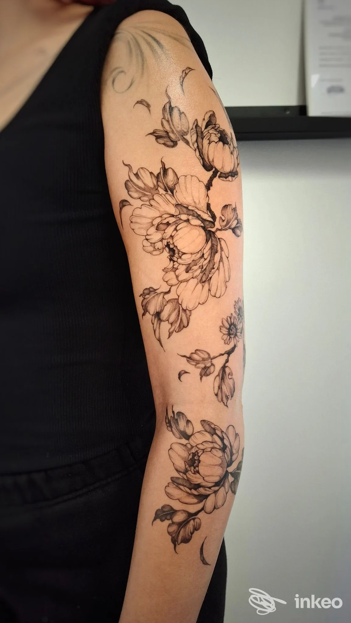 Tatuaggi floreali in nero che decorano braccio e avambraccio, foto fornita da Miriaddormento Tattoo Studio, Chiavari.