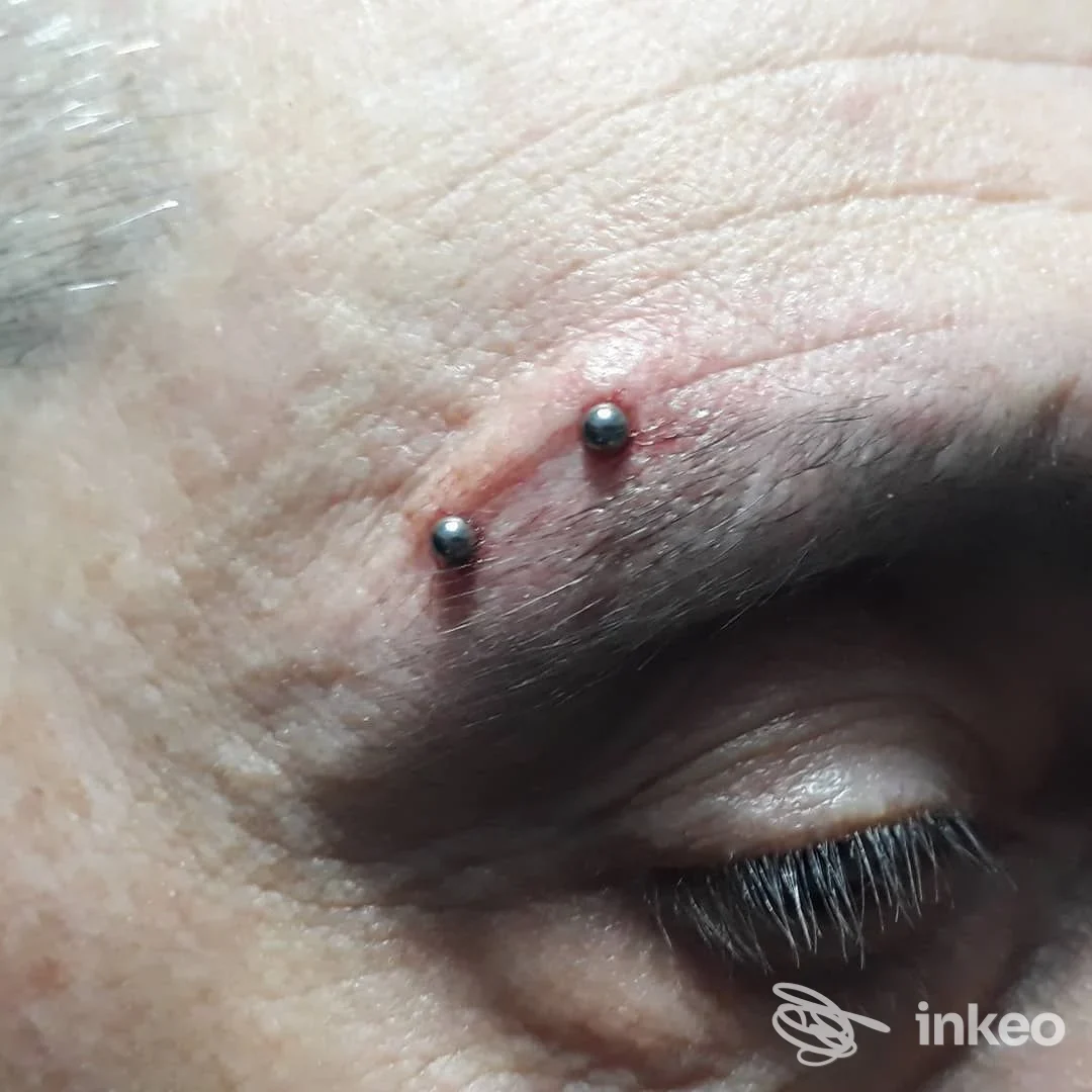 Primo piano di un piercing al sopracciglio eseguito da Moai Body Piercing, Genova, con due sfere metalliche visibili sulla pelle.