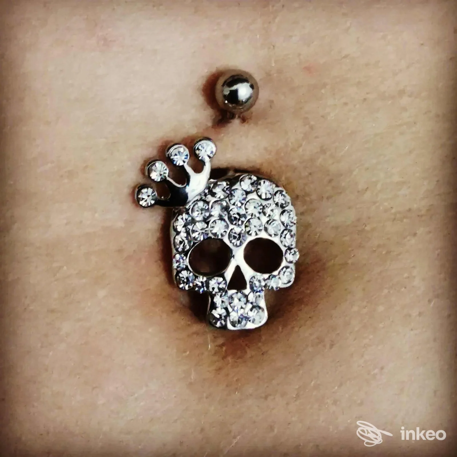 Primo piano di un piercing all'ombelico con gioiello a teschio strass, foto per Mattia A. Tattooer, La Spezia.