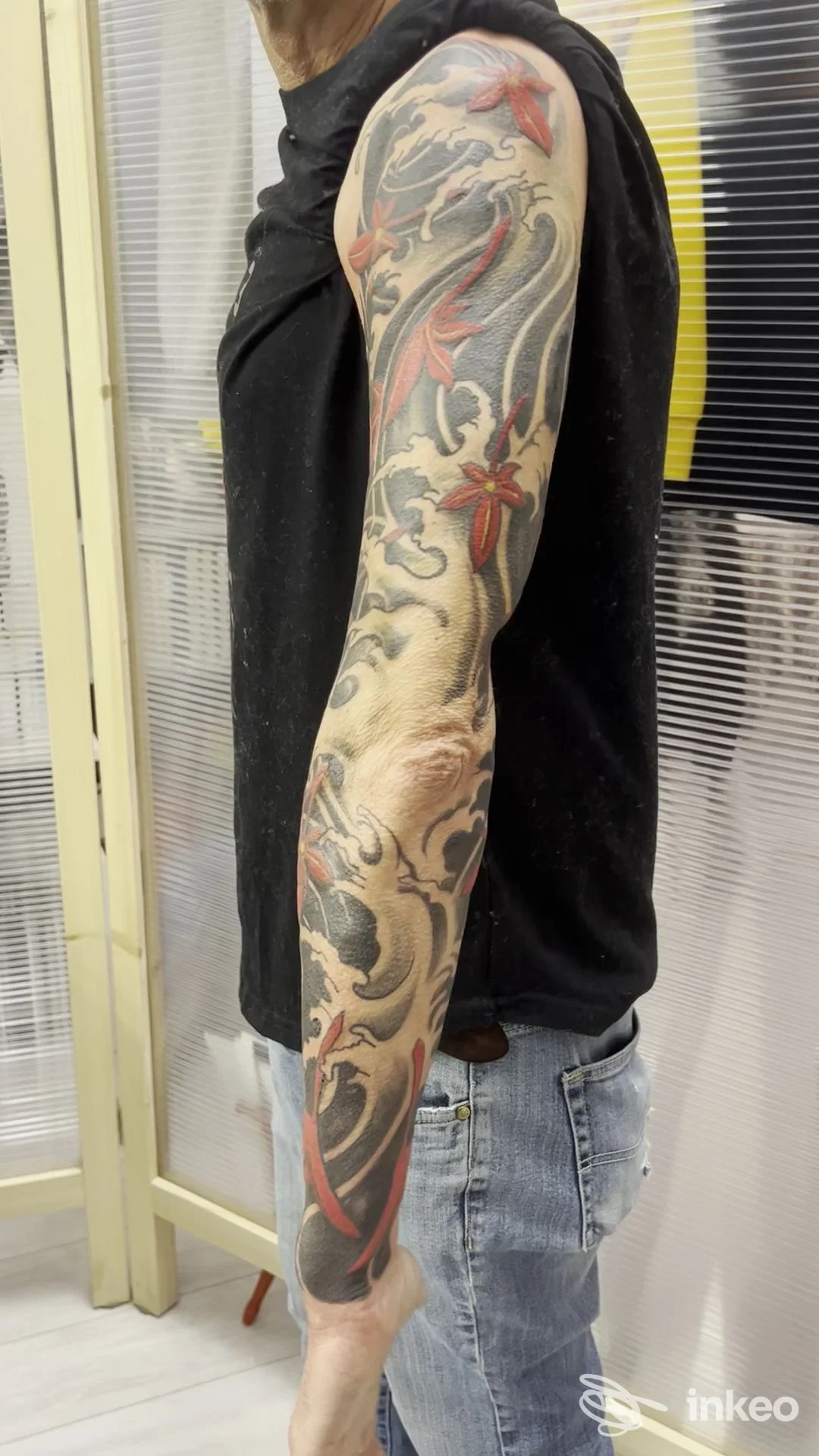 Manica completa su braccio destro con motivi floreali e onde in nero e rosso, realizzata da Morotattoo, Genova.