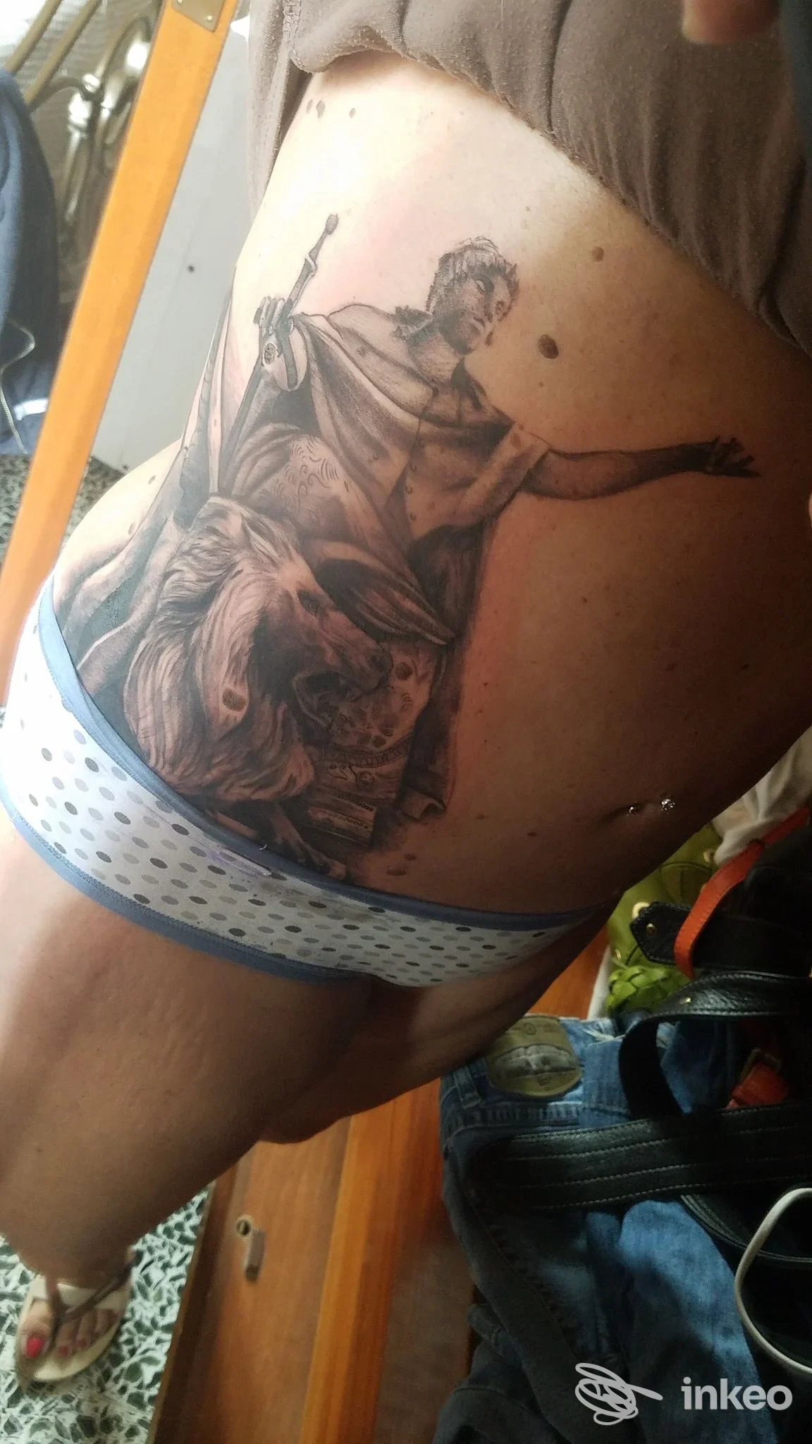 Grande tatuaggio realistico sul fianco con figura classica e leone, realizzato da Orione Tattoo a Imperia.