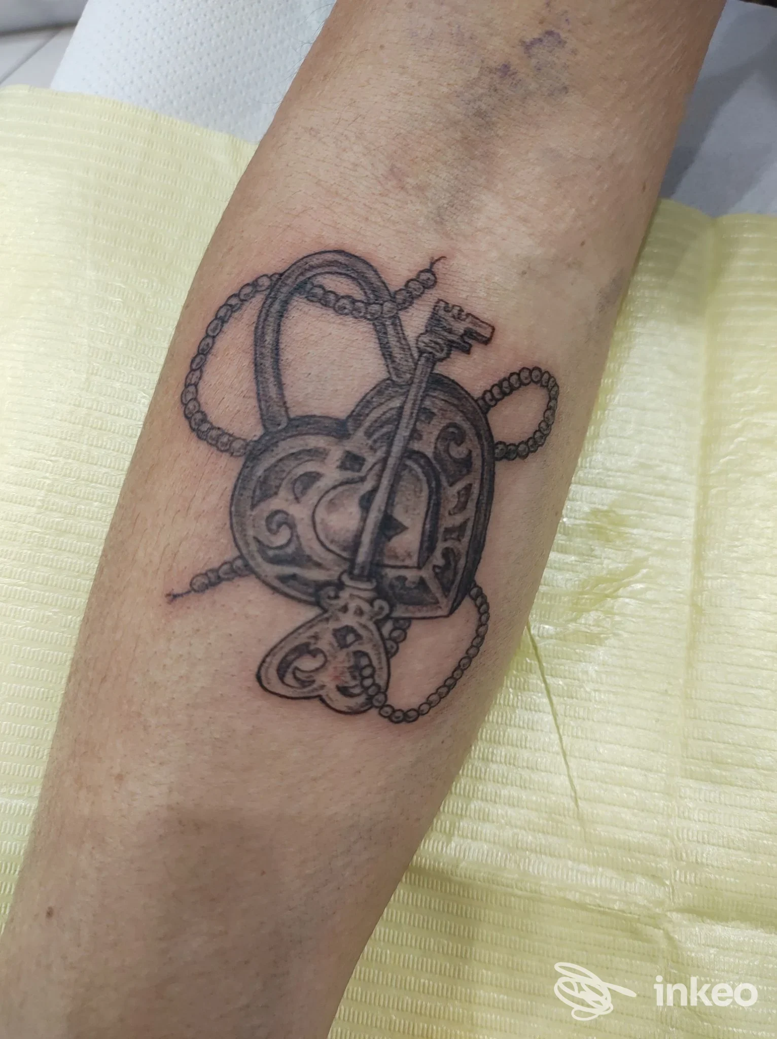 Tatuaggio in bianco e nero su avambraccio: lucchetto a cuore con chiave e catena, Precious Skin Tattoo, San Bartolomeo al Mare.