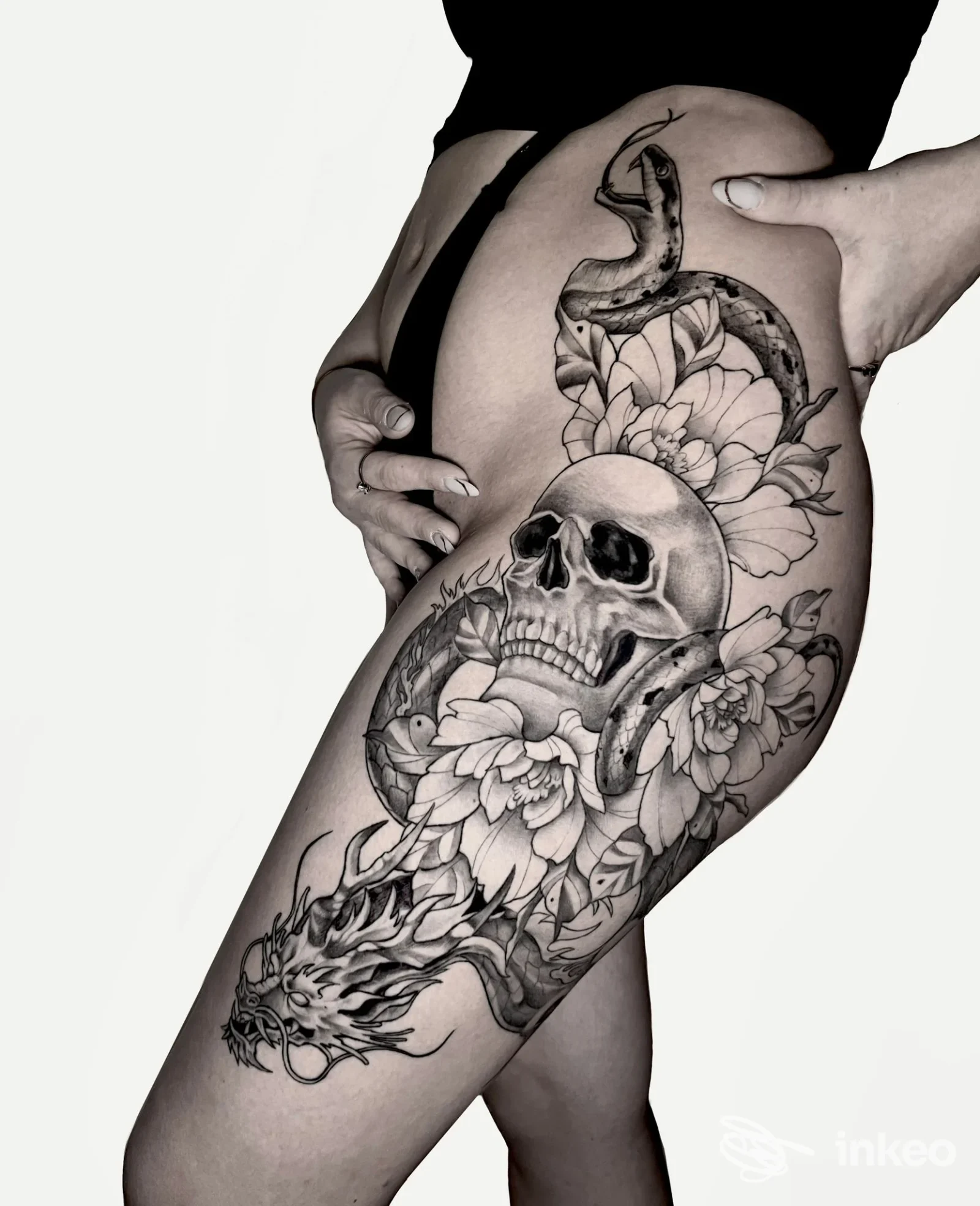 Tatuaggio realistico su coscia con teschio, fiori e serpente eseguito da Red Cat Tattoo & Art Gallery a Genova.